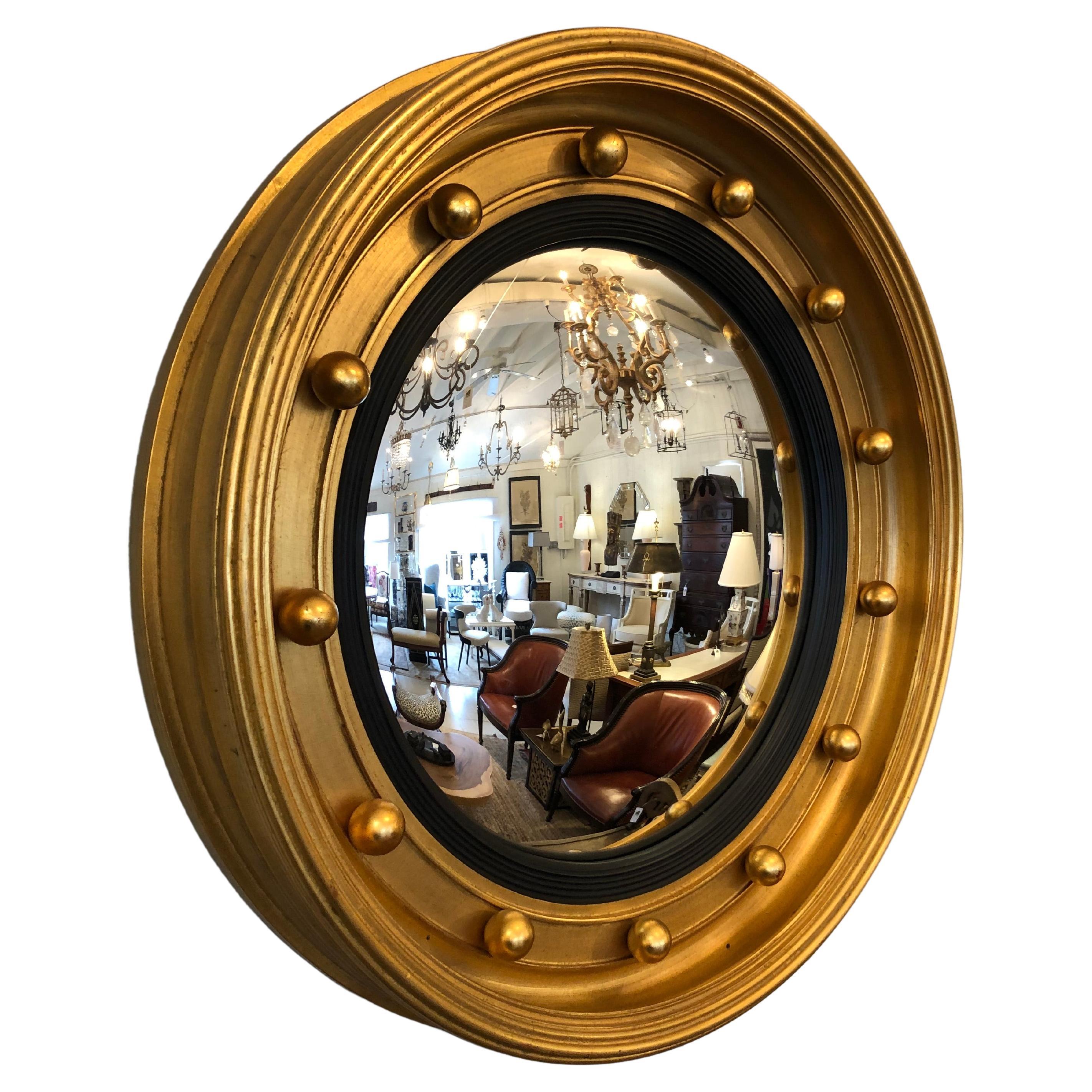 Moderne Interpretation eines runden, konvexen Spiegels im neoklassischen Stil mit einem extrem klobigen Rahmen aus vergoldetem Holz und einer dreidimensionalen Kugelverzierung.  5,5