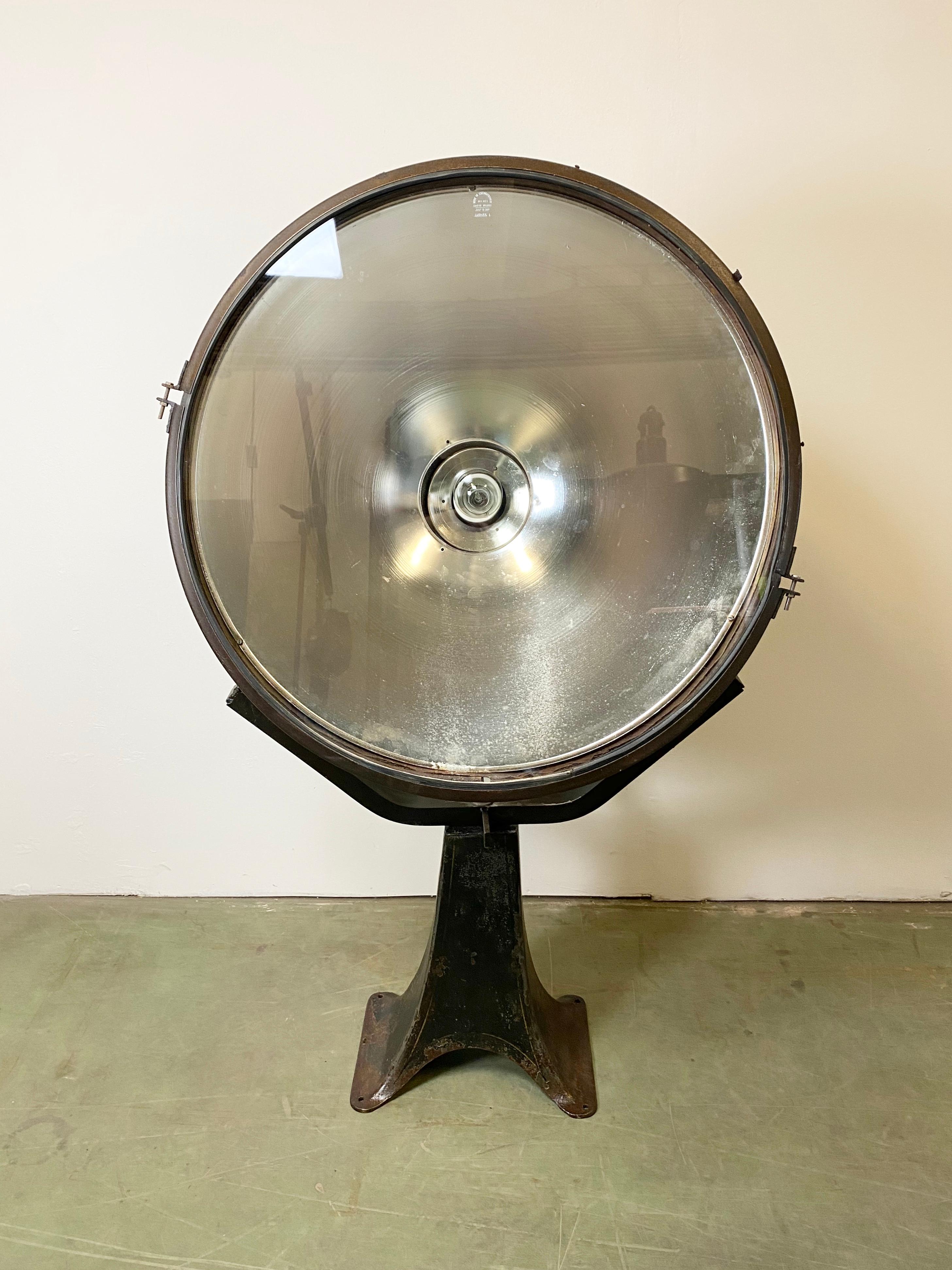 Very large industrial spotlight mounted on a solid iron stand. Made in former Czechoslovakia during the 1950s. It was used in factories and airport runways. It features a metal body, clear glass cover, new porcelain socket for E 27 lightbulbs and