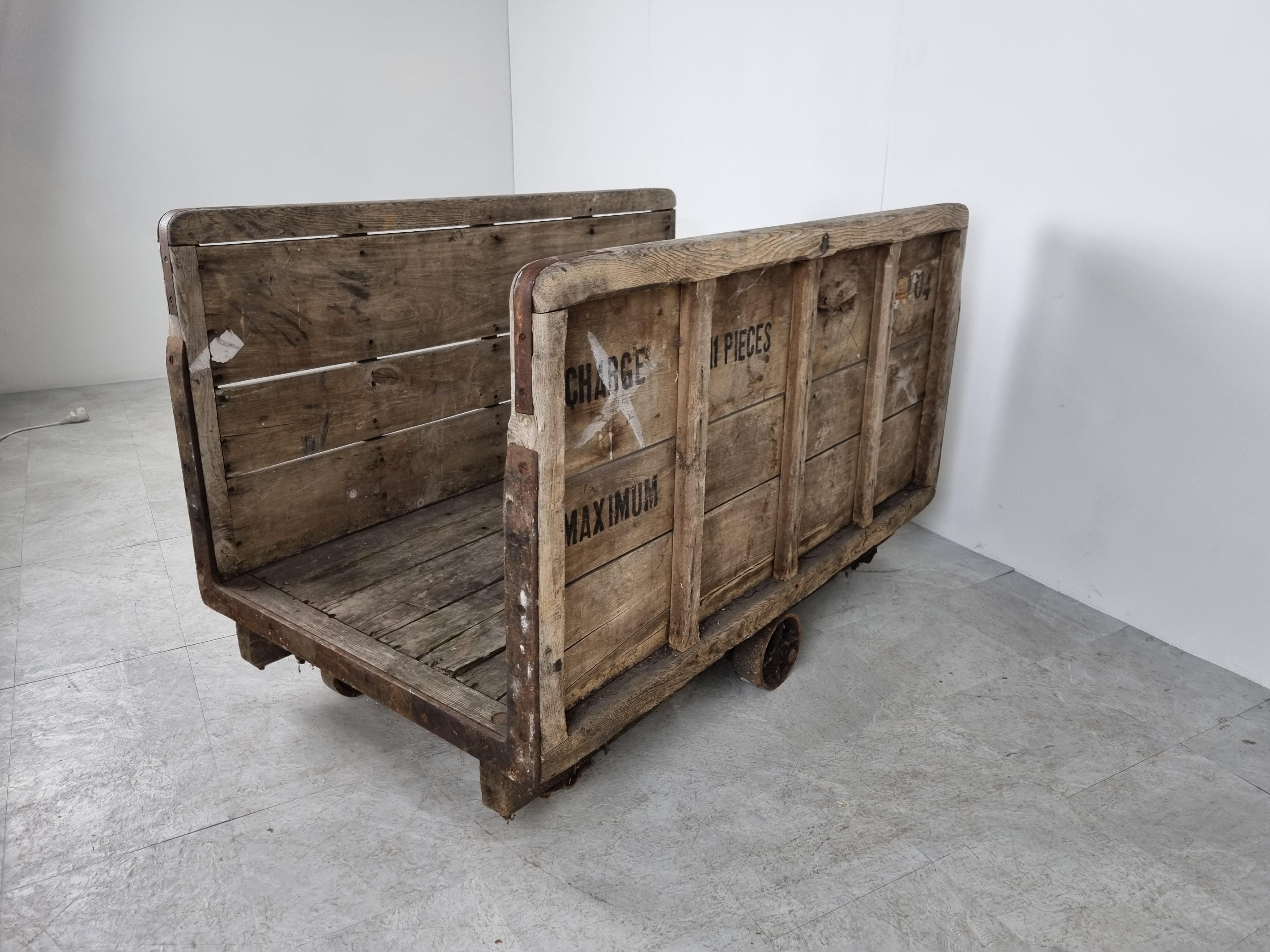 Very large antique industrial trolley/warehouse cart made from thick wood and cast iron wheels.

This heavy duty cart was probably used in a big factory where a few of these carts would have been used to transport products within the