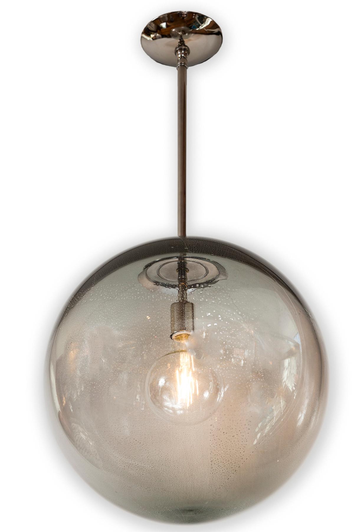 A wonderful set of very large mouth blown globe shaped pendants in a light gray with silver.  The silver offers a subtle texture with speckling and light overall shimmery quality upon illumination.  Each globe while the same color are unique in its