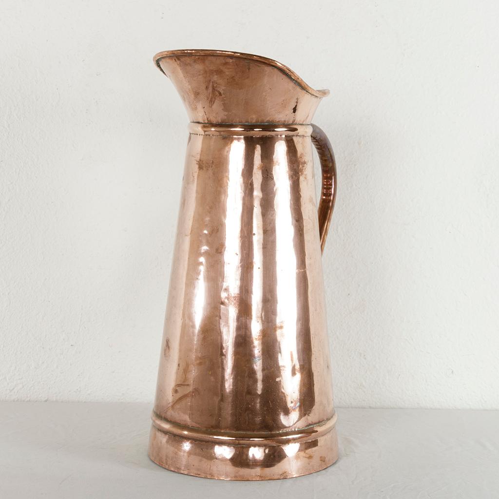 Standing at 20 inches in height, this very large late 19th century copper pitcher from France features hand-hammered sides and a copper riveted handle. Originally used in a Normandy manor house in the kitchen, this artisan-made copper piece with its