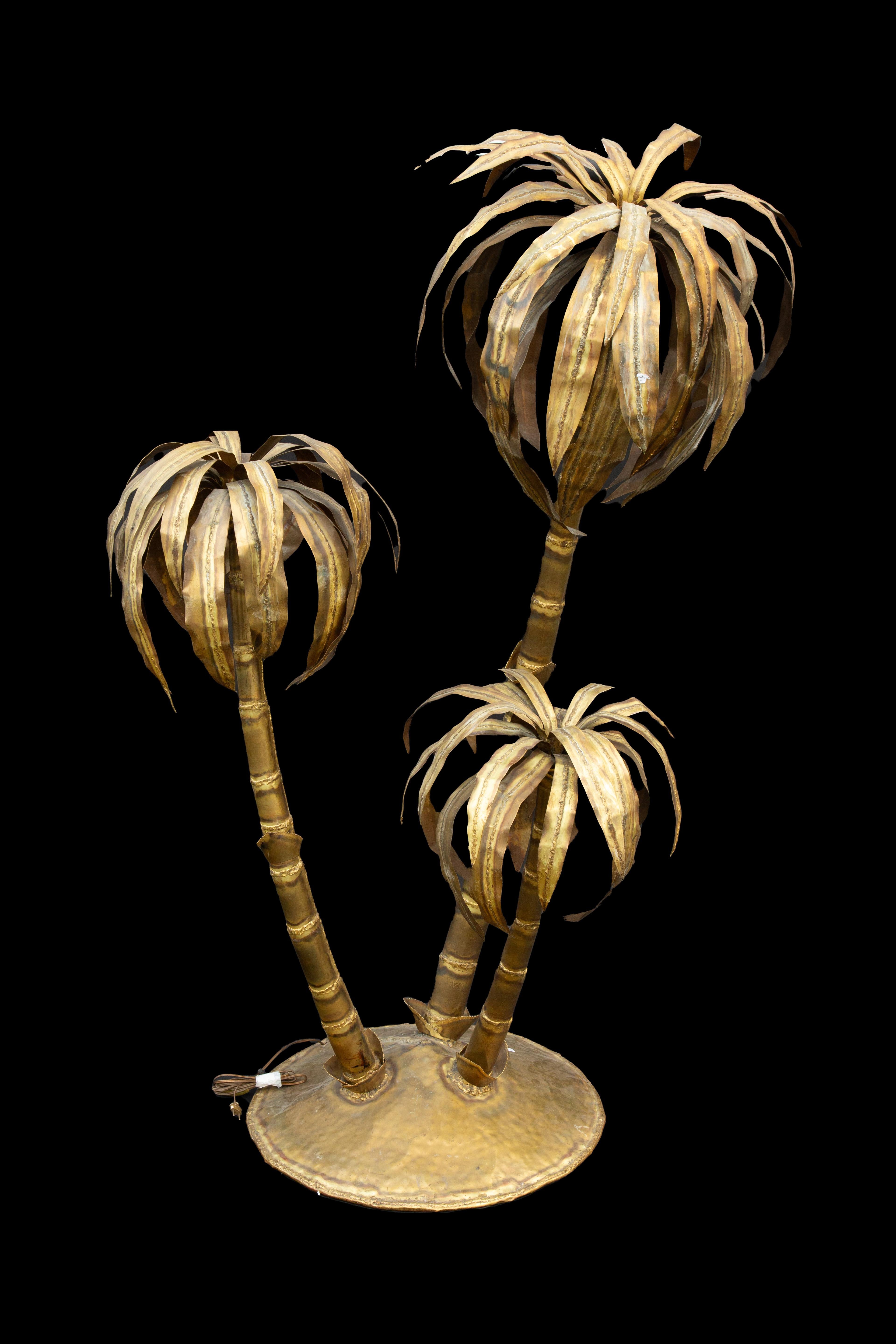 In the style reminiscent of Maison Jansen from the 20th century, this impressive lamp showcases three brass palm trees standing tall and independent. With a height of 77 inches the lamp commands attention and radiates an air of grandeur. Each palm