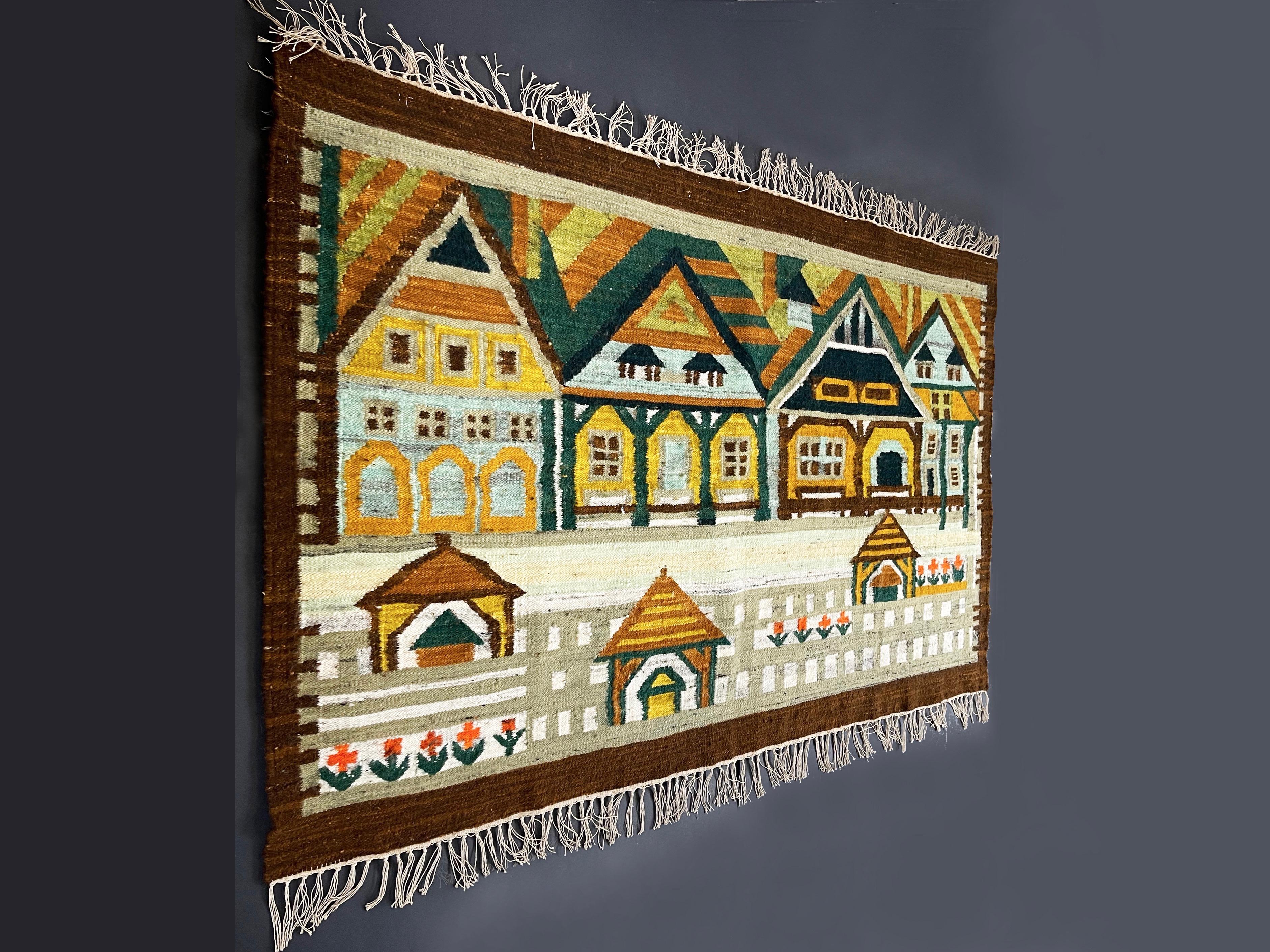 Handgefertigter Vintage-Wollteppich von (attr.) Maria Janowska für Cepelia, Polen.
Wunderschön gestaltete und ausgeführte ländliche Szene mit traditionellen Häusern und Blumen.
Der gesamte Wandteppich ist in warmen und erdigen Tönen gehalten, wie