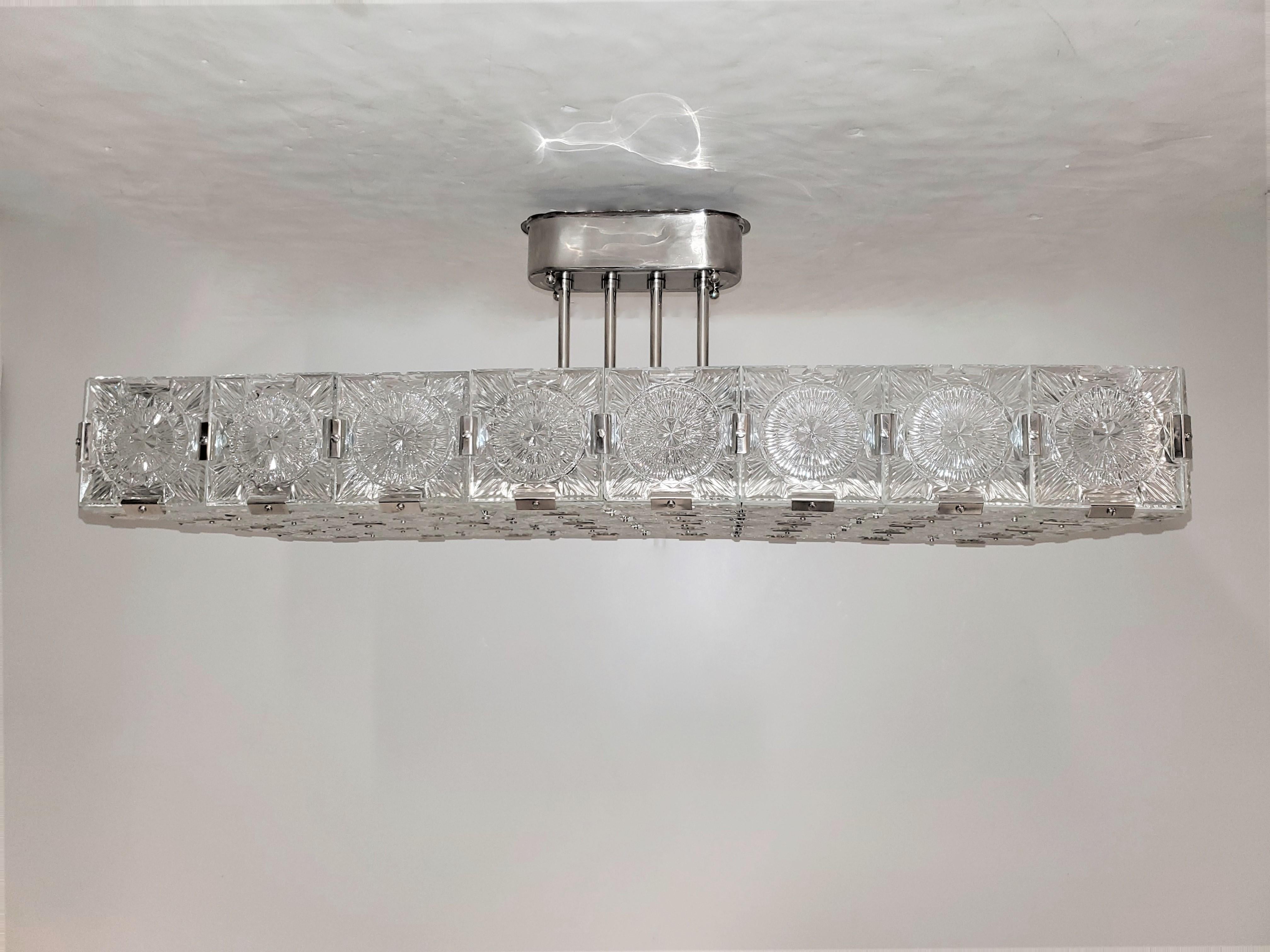 A fabulous and striking rectangular modernist chandelier comprising 44 panels of glass shaped as a large rectangle, formed together with original nickeled bronze brackets and supported by an oblong canopy with fluted double rod stem. The