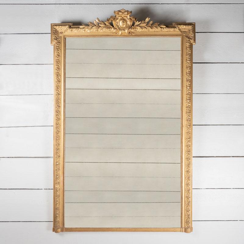 Très grand miroir en bois doré sculpté d'une large bordure de motifs floraux, petit fronton. Magnifiques dorures d'origine, miroir argenté et parquet en bois.
Période Napoléon III - France 19ème siècle.

Hauteur 204 cm - 80,32