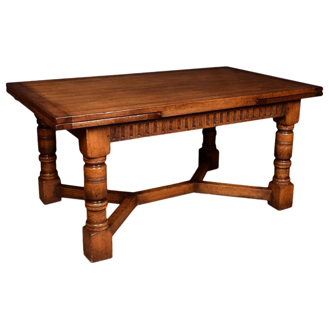 Oak draw leaf refectory table, the rectangular solid oak top above two pullout / pull-out ends, to the ed frieze above massive turned gun barrel legs joined by a double Y-shaped stretcher.
Dimensions:
Height 30.5 inches
Width 66 inches when open