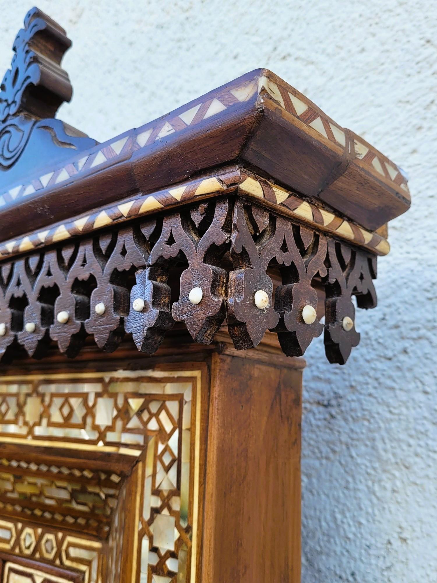 Très grand miroir de style oriental, avec décor en bois sculpté, marqueterie géométrique de bois, de nacre et d'os, arc mauresque, cartouche avec inscription arabe stylisée

Tout l'espace est couvert par cet incroyable travail de marqueterie.

Belle