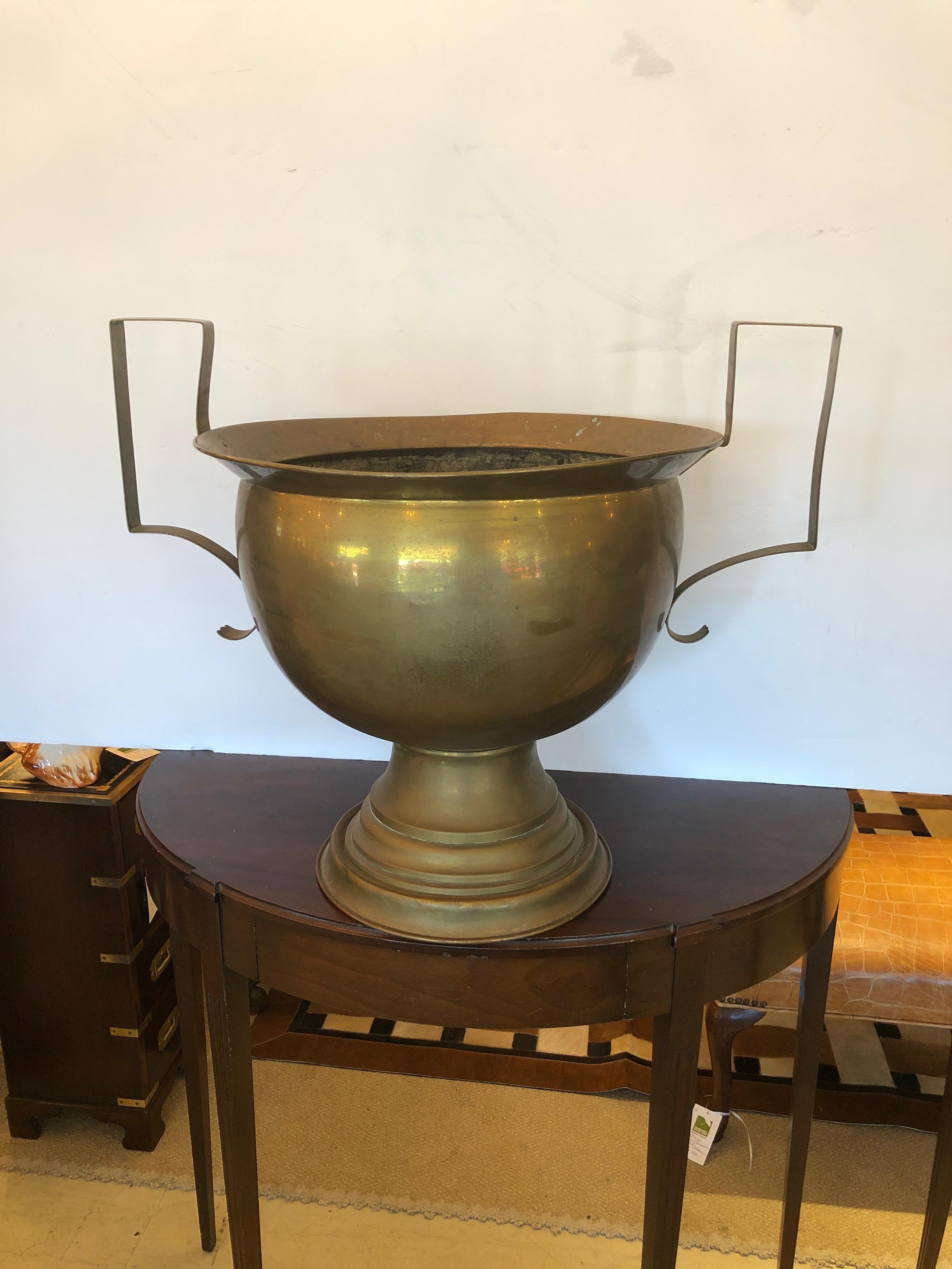 Eye catchingly large in scale and Classic pair of brass urns, planters, flowerpots or centerpieces, having handsome bases and neoclassical simple shaped handles with copper rivets.

Measures: 18 H to top of urn
22 H to top of handles.