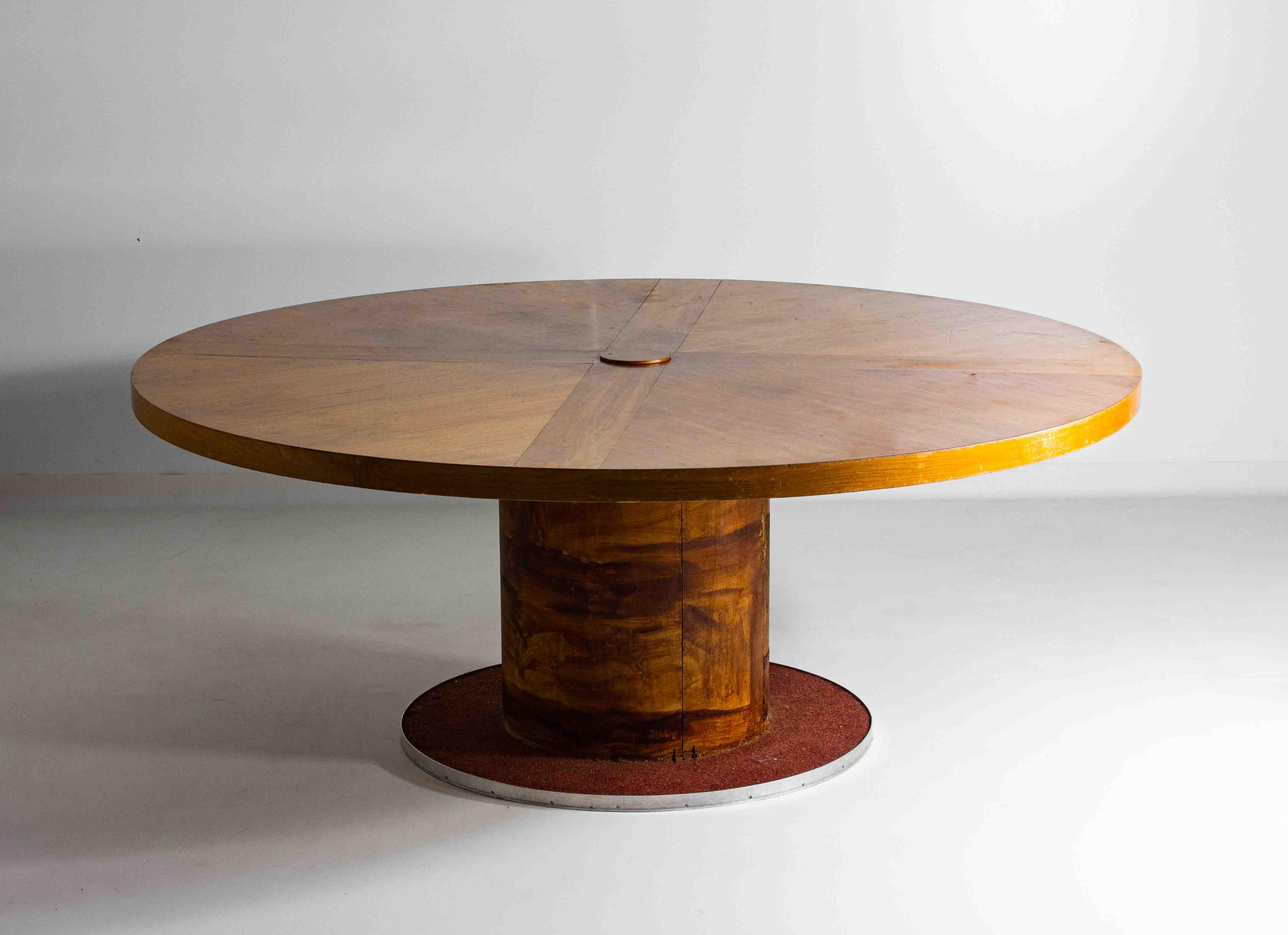 Questo grande tavolo da pranzo rotondo vintage degli anni '60 presenta un sorprendente piano in radica e una robusta base centrale con piedistallo. Con un diametro di 186 cm, offre un ampio spazio per pranzi e cene. Il tavolo presenta i ricchi e