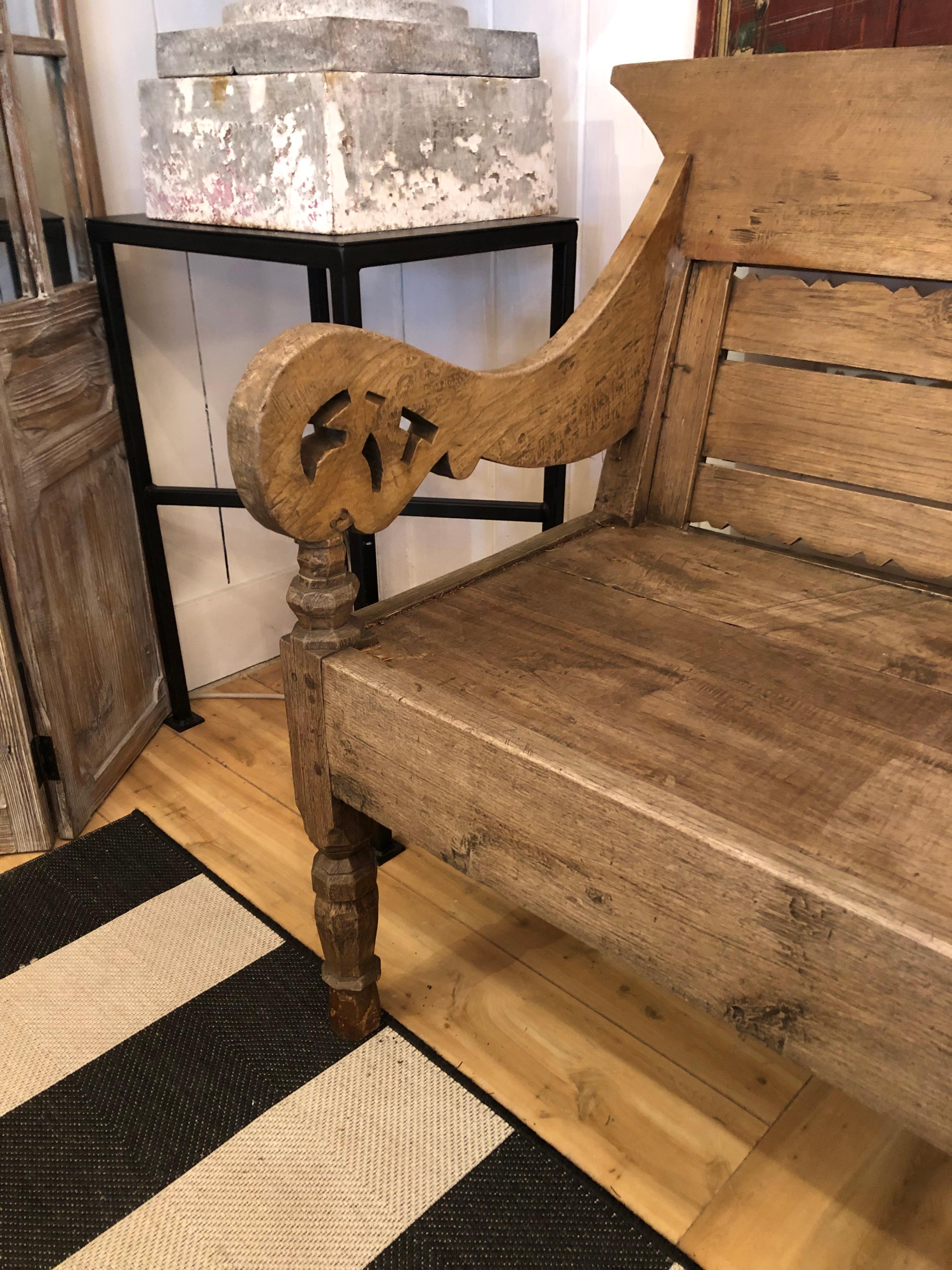 Impressive in scale carved rustic teak bench having slatted back, gorgeous curvy scrolled arms and turned legs.  Sourced in Jakarta.  Warm and character rich patina.
72.75 width arm to arm
arm height 30.5