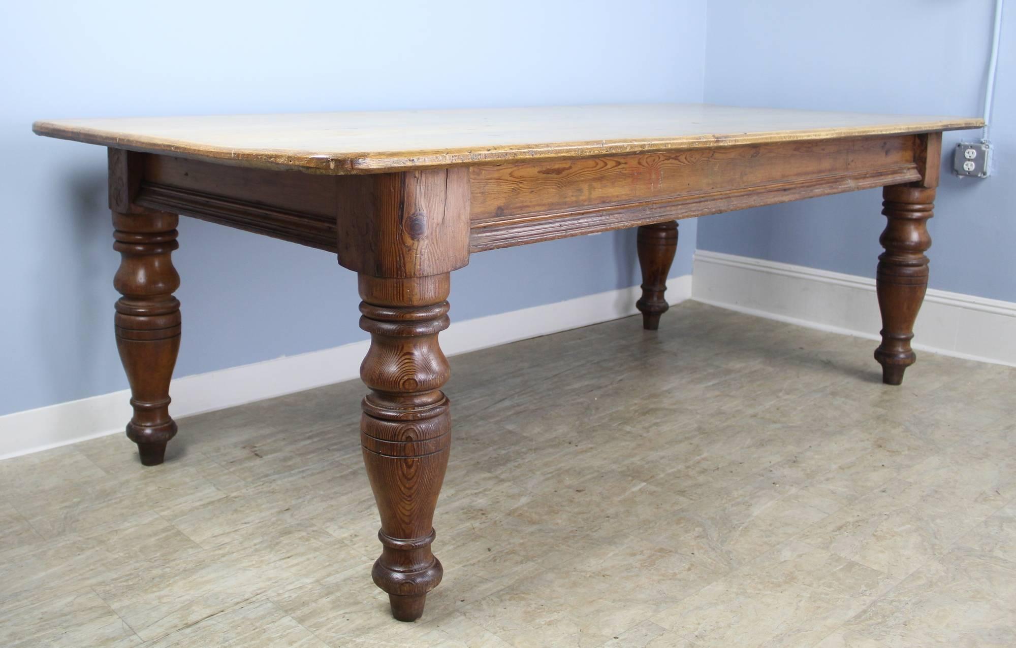 An exceptionally deep and largely proportioned pine farm table with a scrubbed blond pine top and big chunky turned legs. A handsome and unique look with interesting distress and real design presence. The 24.5 inch apron height is good for knees and