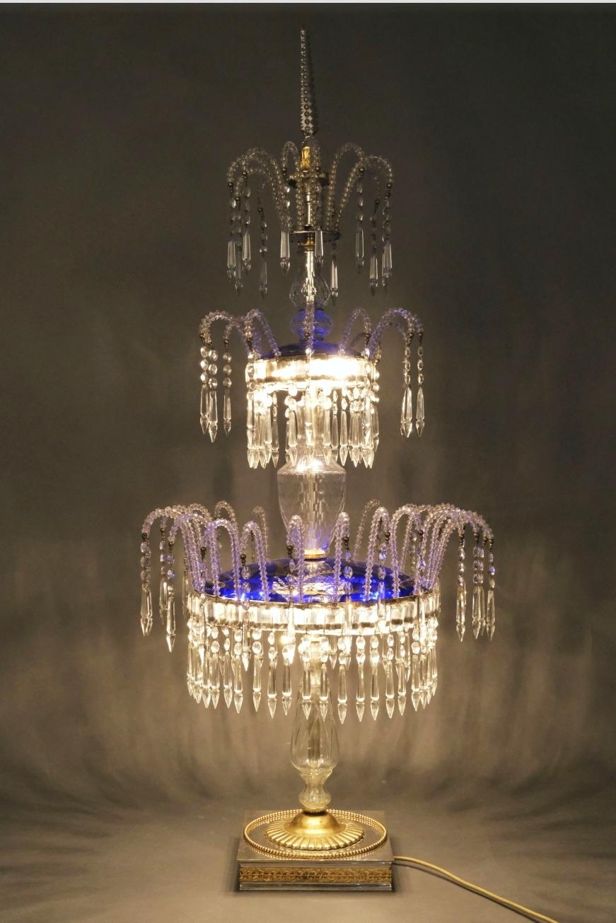 Very beautiful and large glass crystal lamp on a silver and gold base. The two illuminated levels are covered with cobalt glass discs with gold paintings. The lamp is crowned by a crystal obelisk. Probably Northern Europe of the 1930s