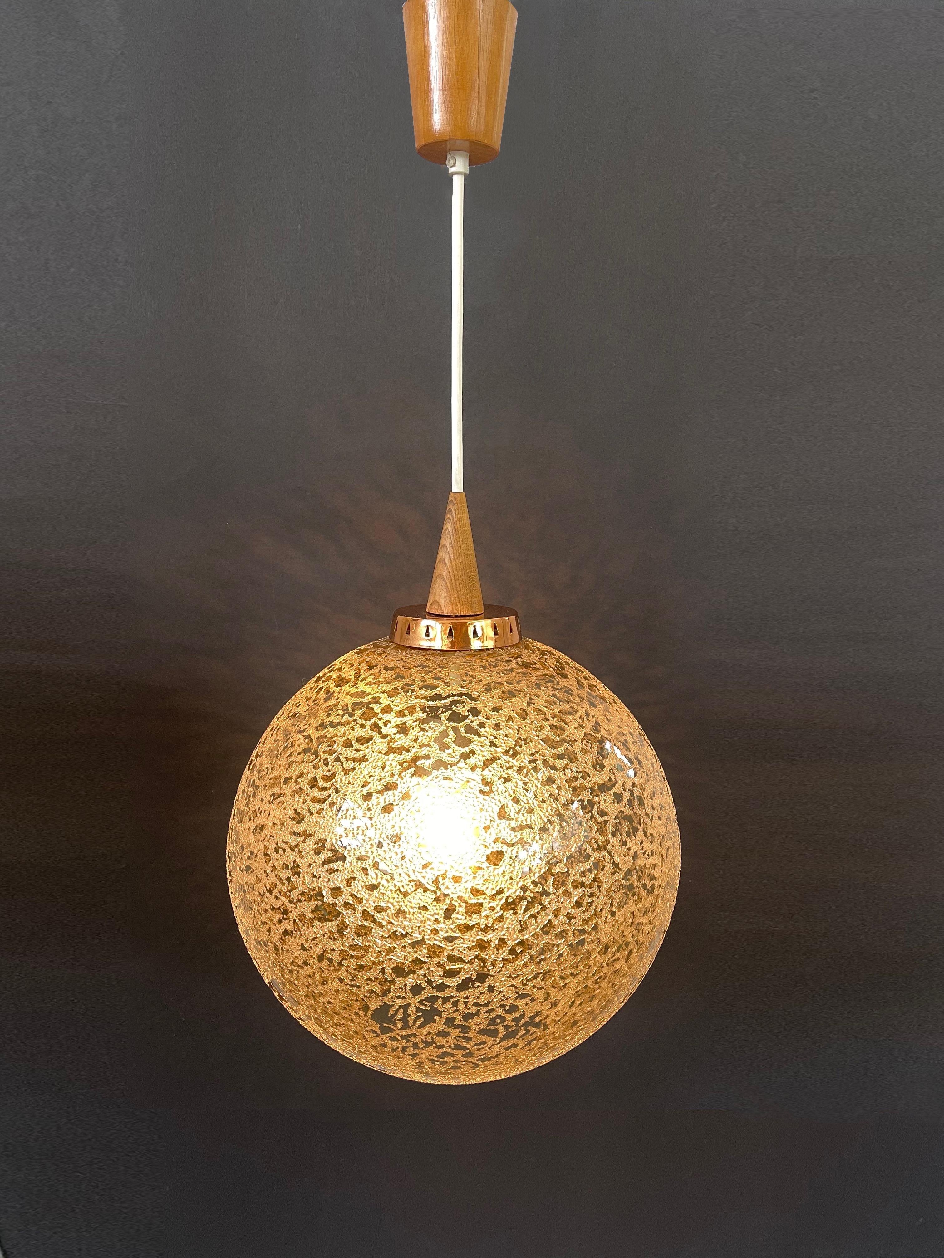 Lampe suspendue magnifiquement conçue dans les années 70 en Allemagne.
Fantastique design dans un brun café fumé clair avec des motifs de cristaux de neige fondante sur toute la surface du globe.
Raccord décoratif en cuivre avec triangles découpés