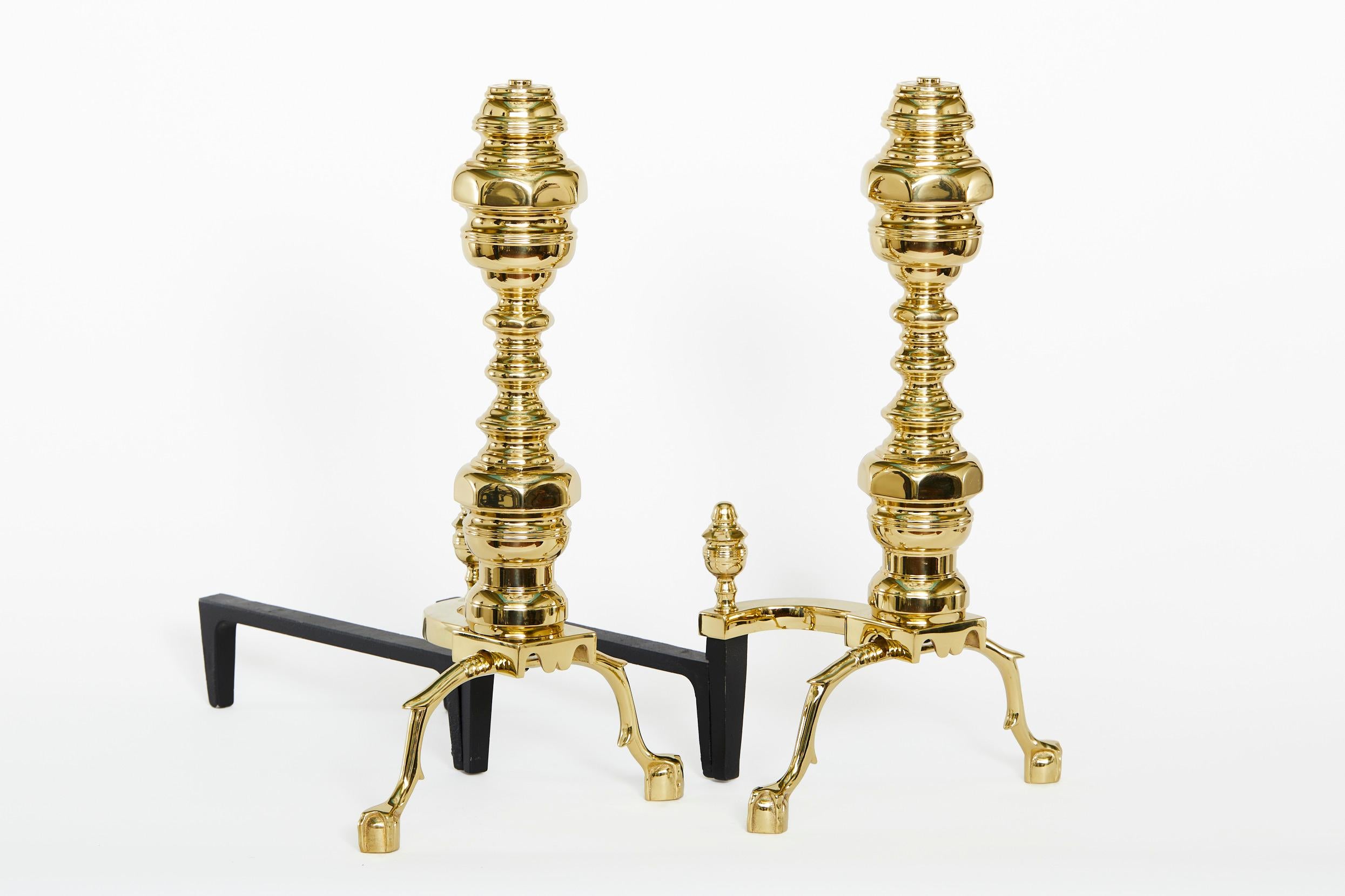 Very large gilt solid brass Georgian style pair andirons with design details feet and urn finial design top. Each andiron is in great condition. Minor wear. Each one measures 23.5 inches high X 13 inches wide X 21.5 inches deep.