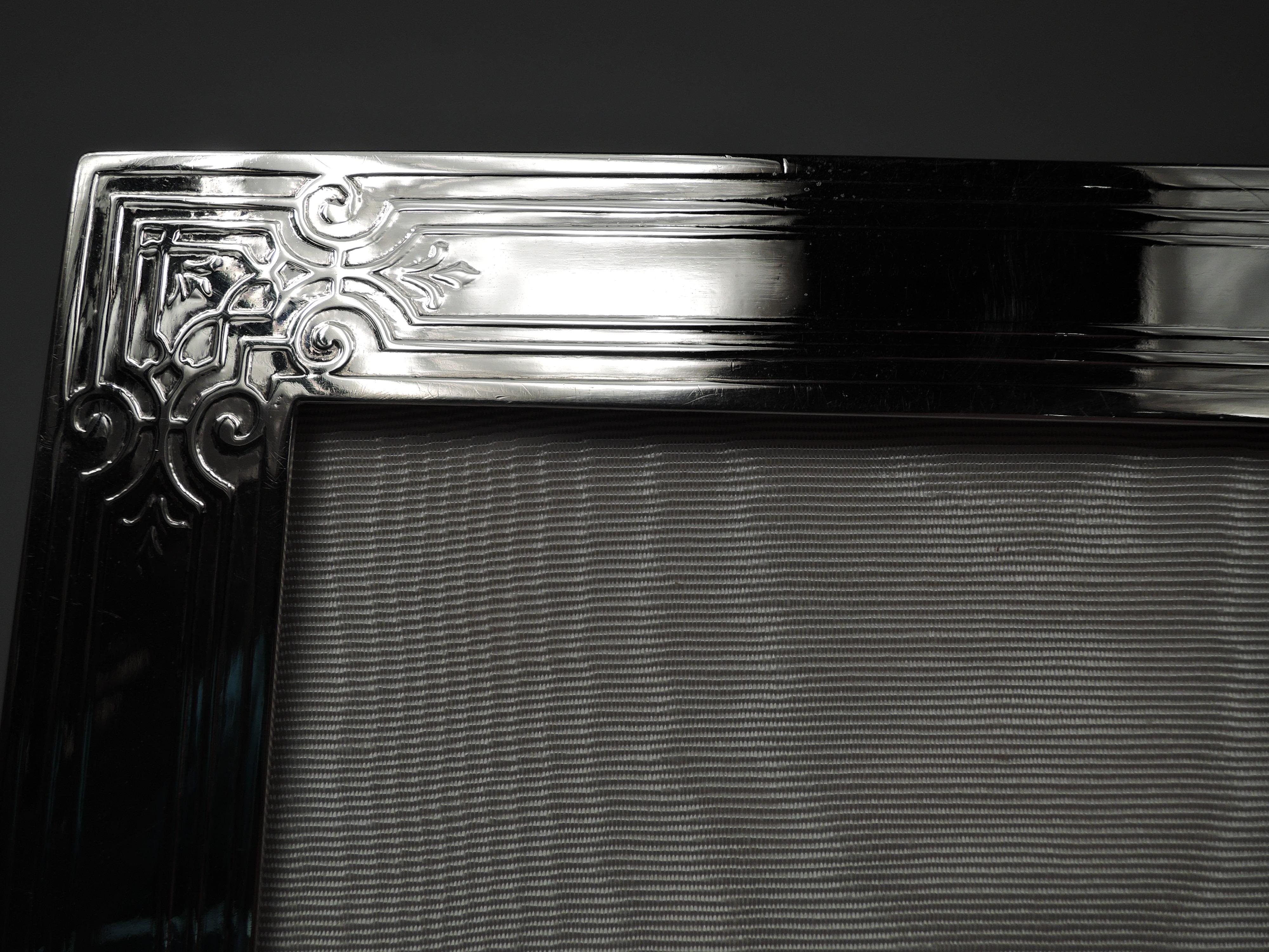 Very large Edwardian Classical sterling silver picture frame. Made by Tiffany & Co. in New York, ca 1910. Rectangular window in flat surround. On front acid-etched curvilinear frames with stylized leaves and fretwork corners. Sides and top have