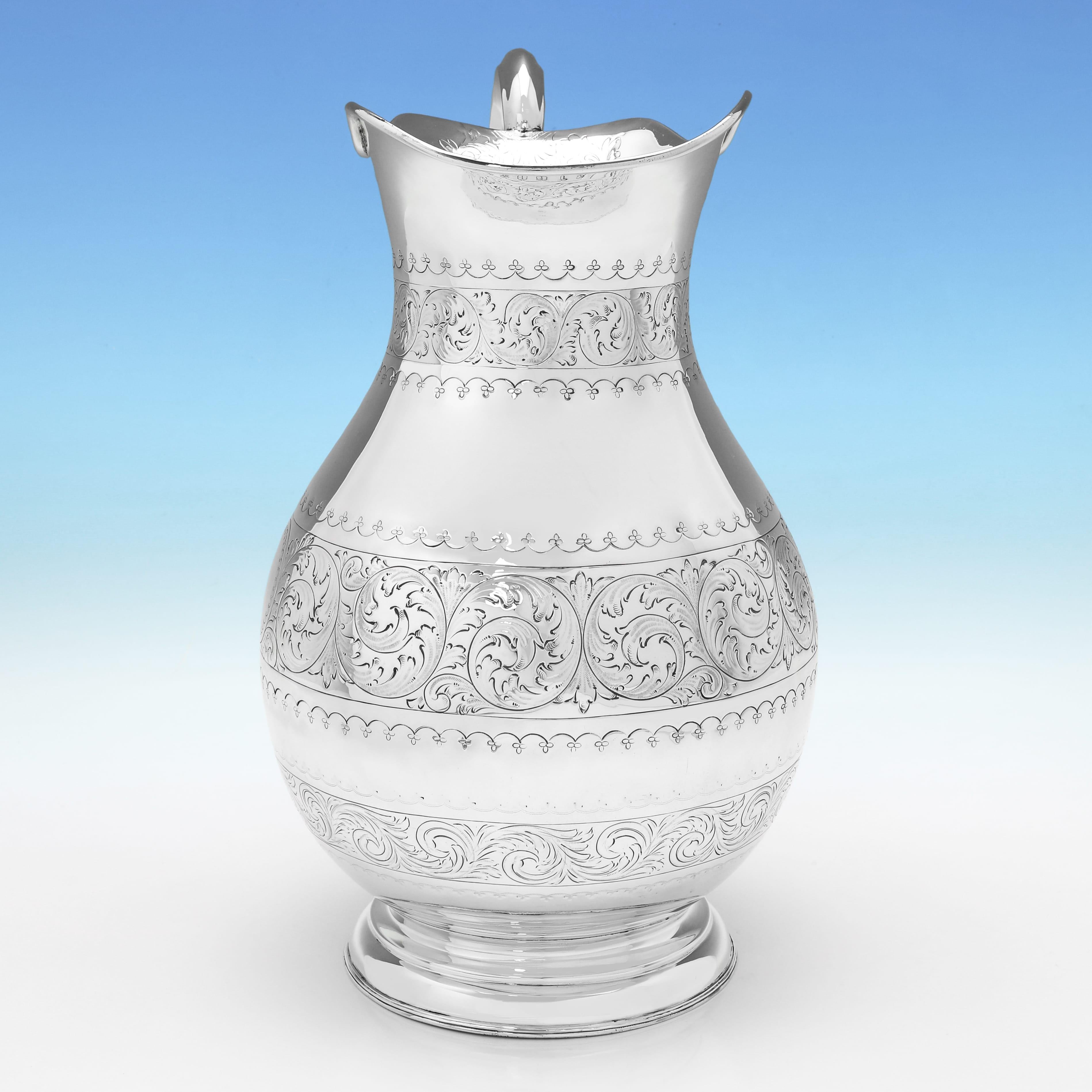 Marcada en Londres en 1898 por James Jay, esta atractiva jarra de agua de plata de ley victoriana, muy grande y antigua, tiene el cuerpo decorado con un cincelado plano y un asa en forma de voluta. La jarra de agua mide 35,5 cm de alto por 27 cm del