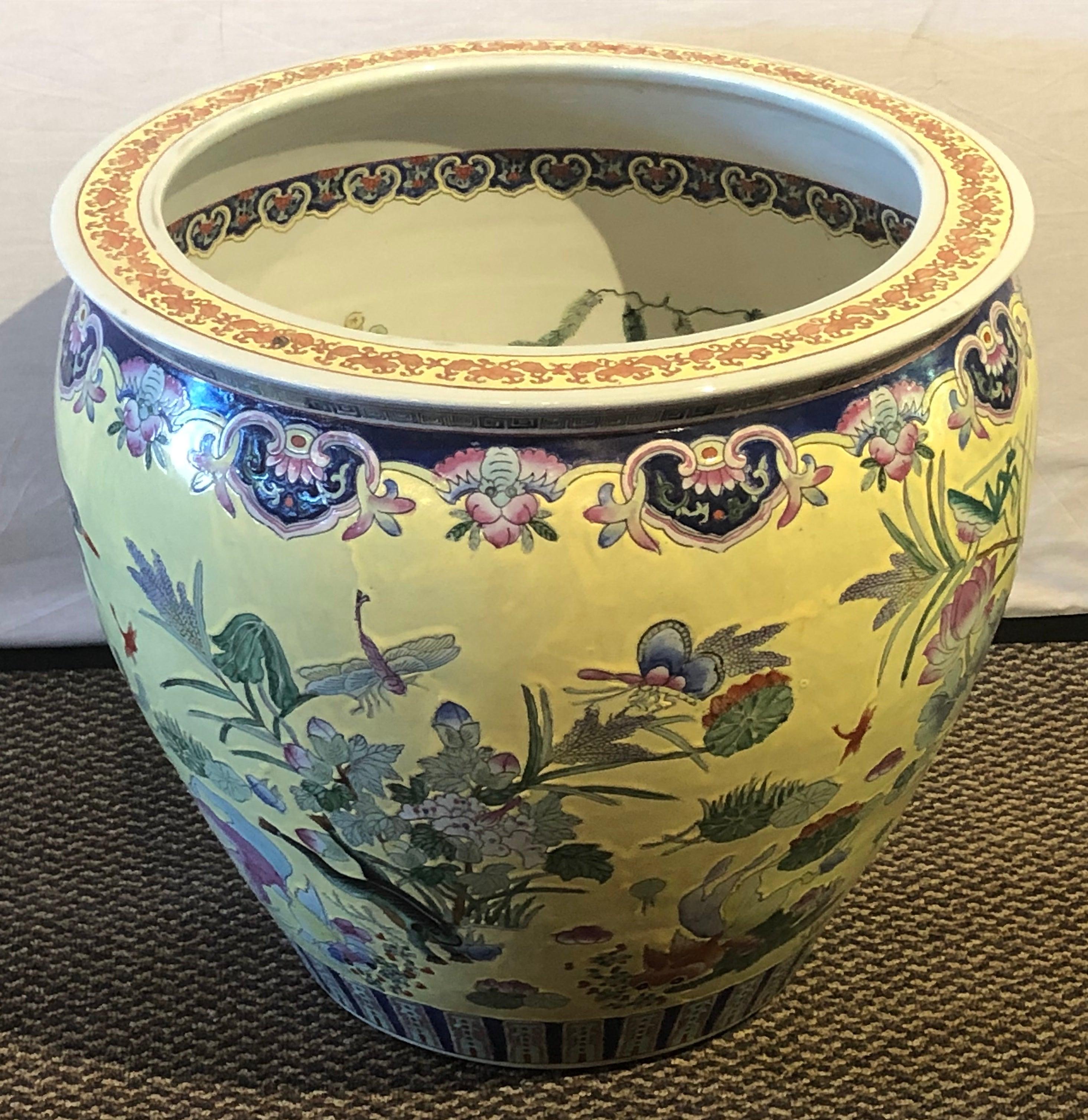 Large vintage late 20th century Chinese Export porcelain jardinière, fish bowl or planter interior and exterior enameled design of fish. Flowers, crickets and others. The large jardinière features a beautiful yellow color and can make a statement in