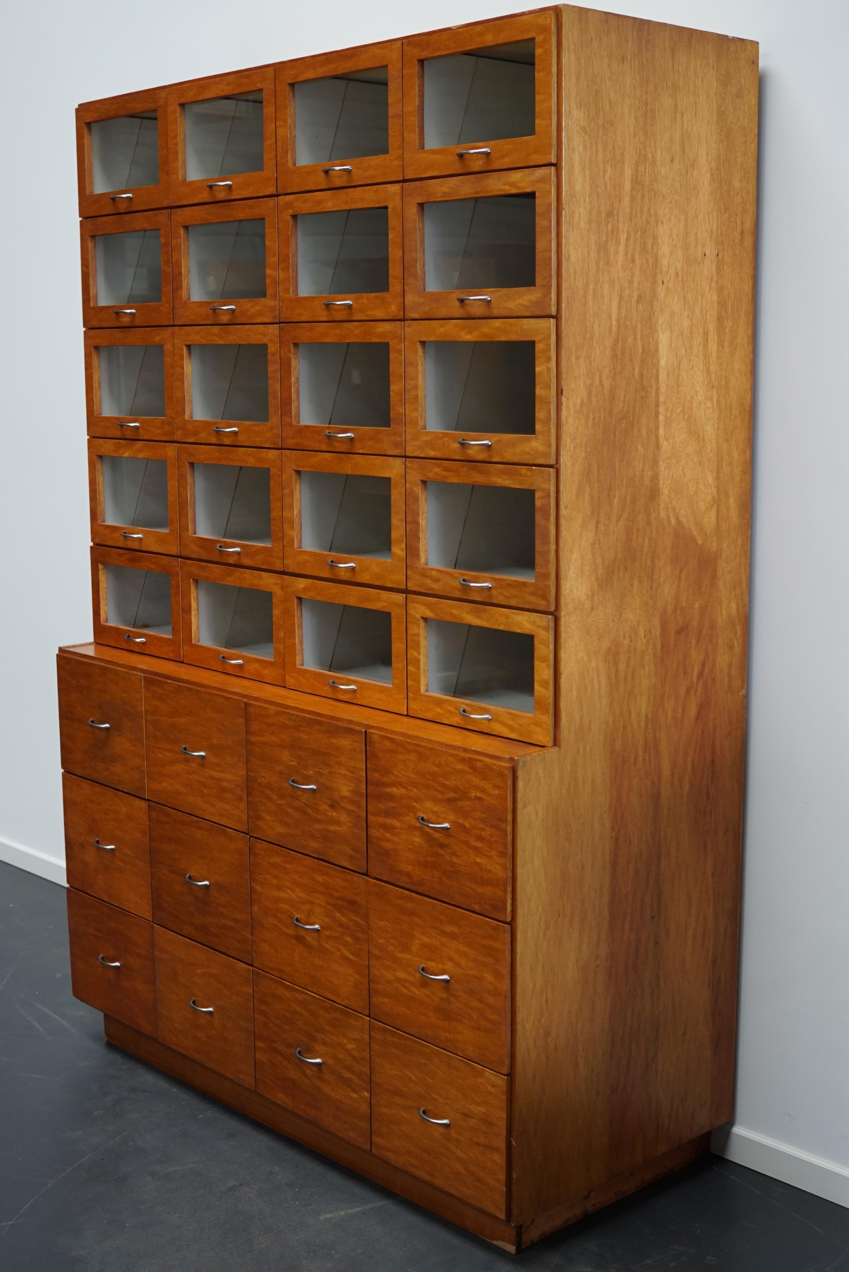 This haberdashery cabinet was produced during the 1950s in the Netherlands. This piece features 32 drawers in oak ply with glass fronts and chrome handles. It was originally used in a shop for sewing supplies and fabrics in Amsterdam. The interior