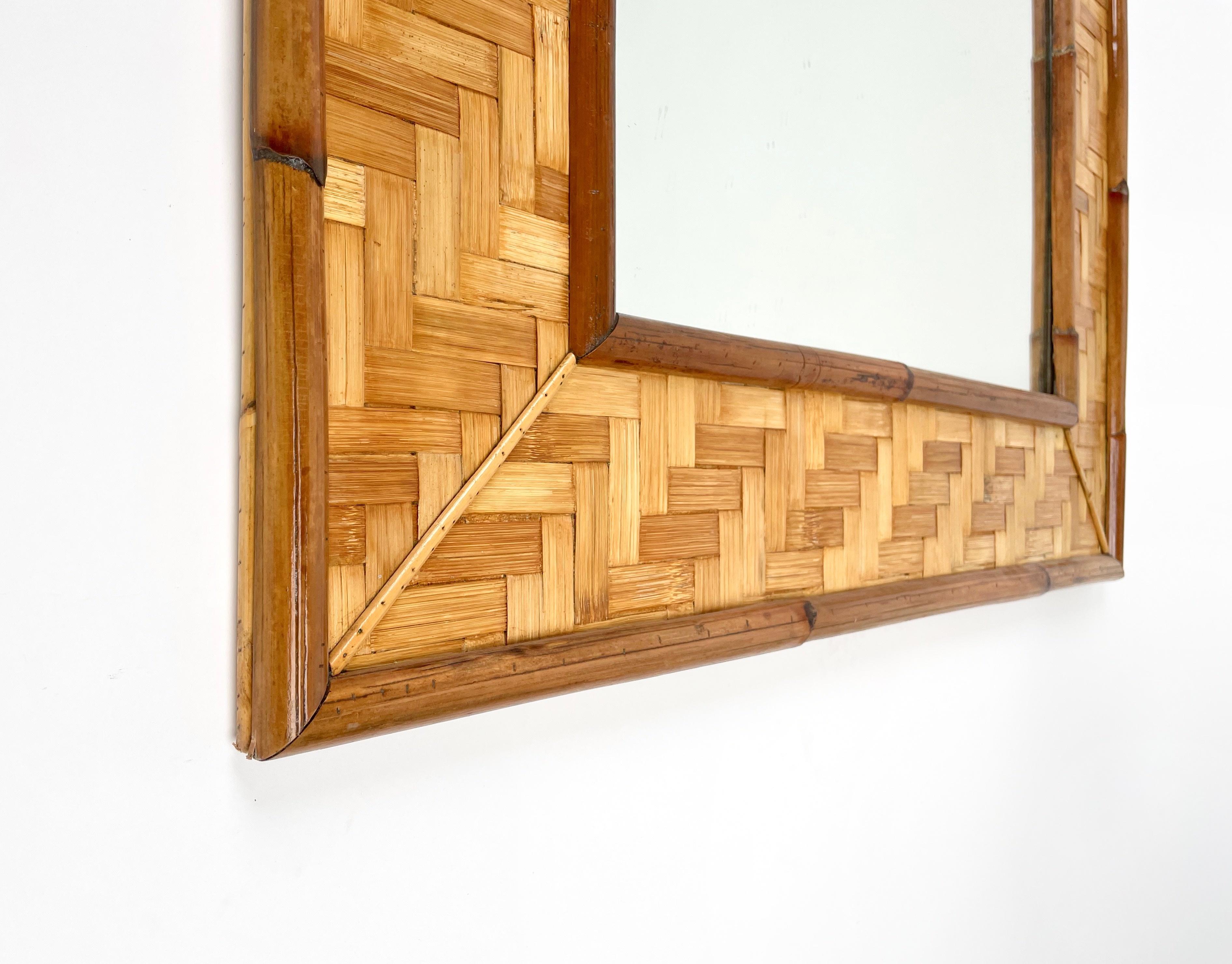 Large vintage mirror dating back to the 1970s and certainly made in Italy.
The wooden structure of this mirror is completely covered in Rattan Parquets which creates a dense texture framed by sections of bamboo and rattan canes.
This mirror comes