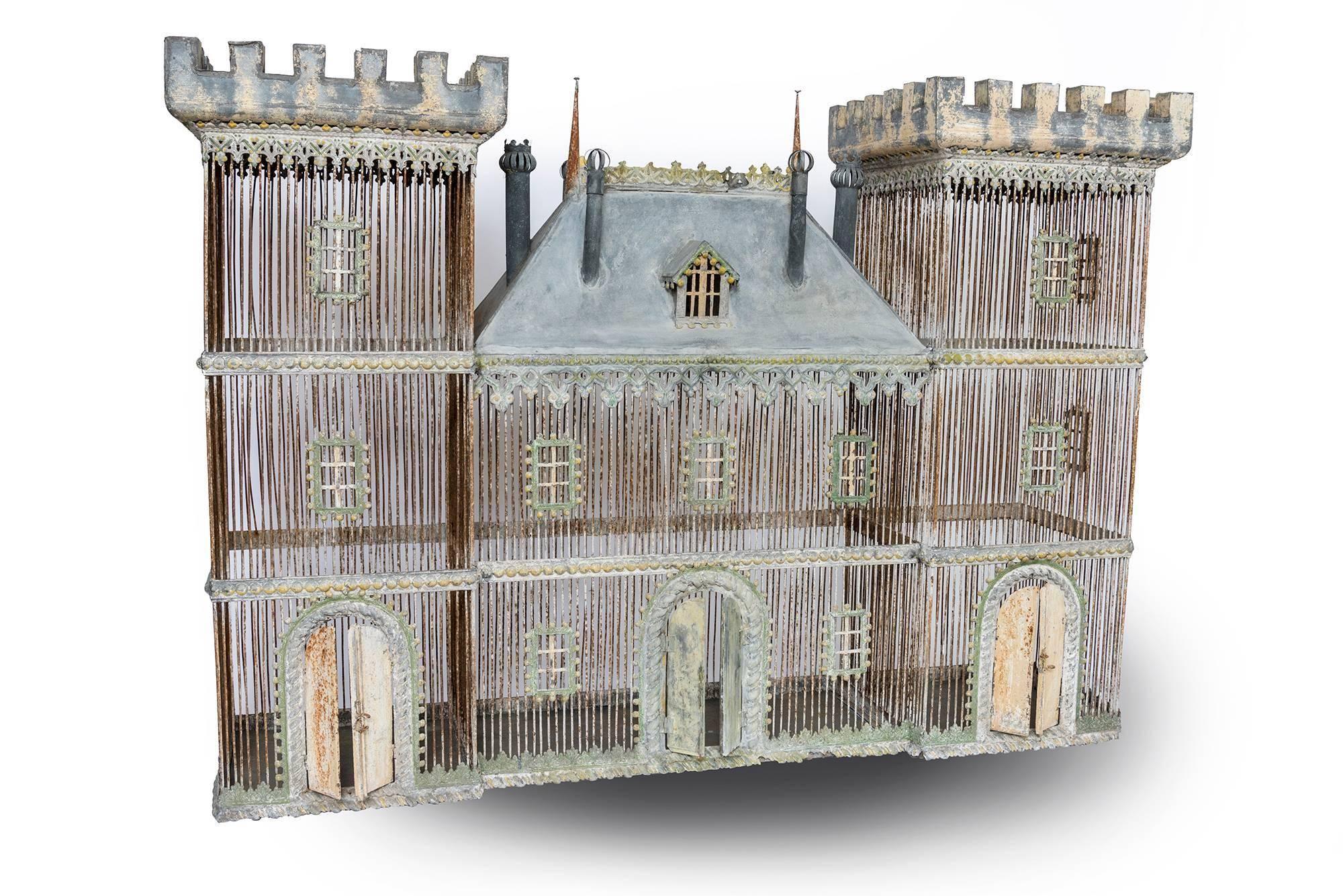 A rare and incredibly beautiful birdcage made in zinc with doors that open. This is in the form of a Medieval castle from France from the early 20th century. Painted in varying colors of green and yellow, with some blue showing through. This would