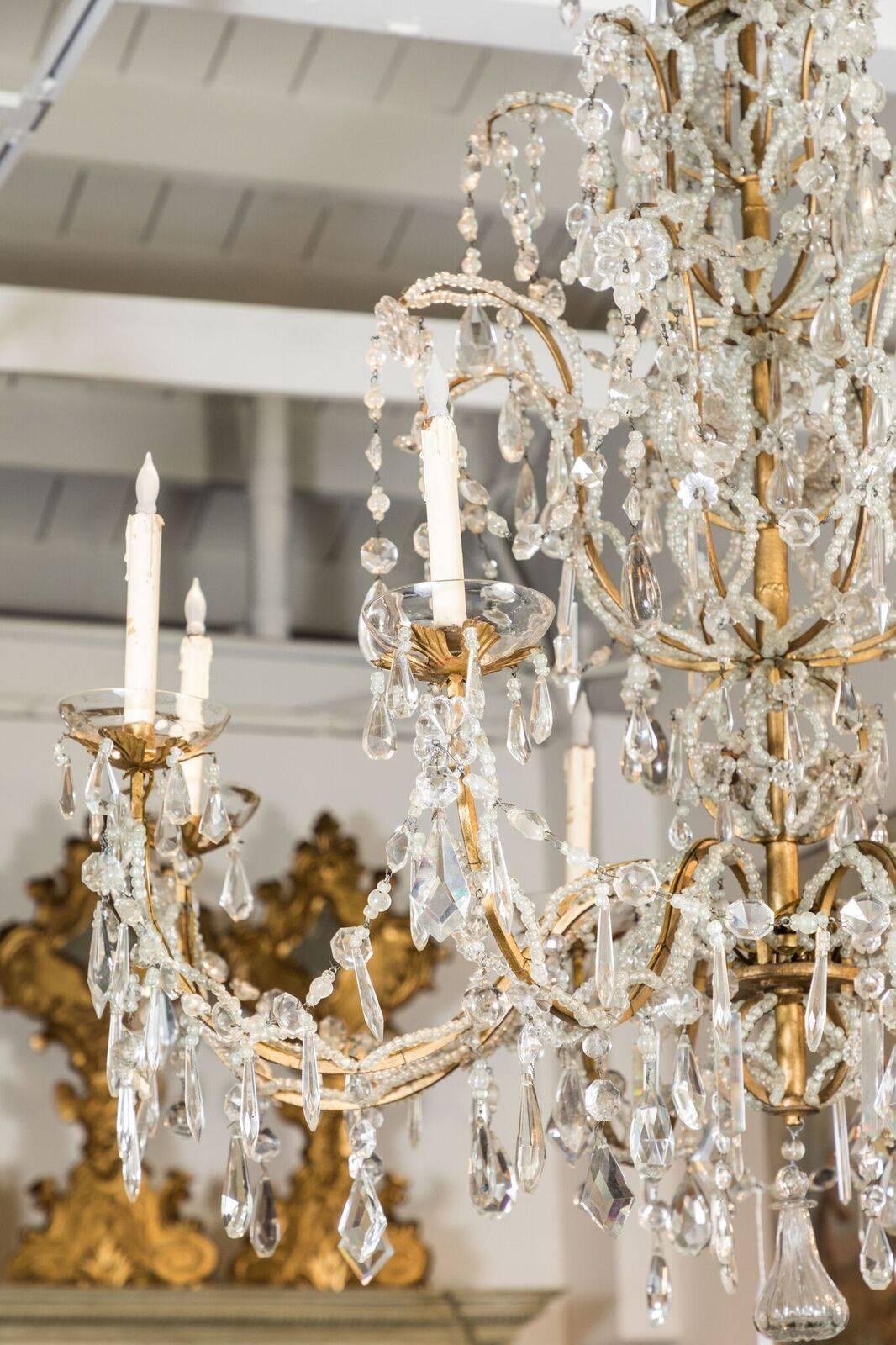 Stunning, eight-light, Italian chandelier featuring hand-beaded strands that mirror the gilt bronze frames. The whole embellished with generous amounts of crystal.