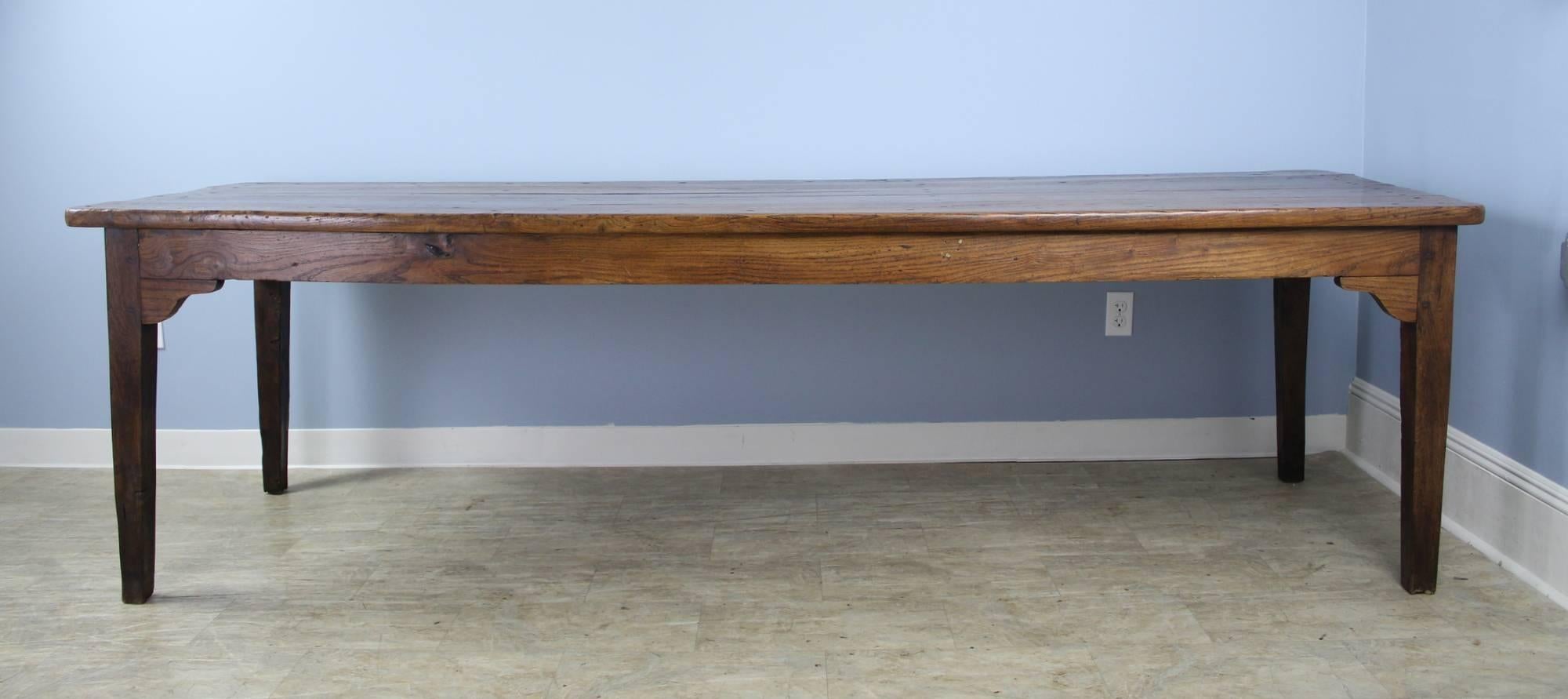 A long rustic elm farm table with glorious grain, a thick top and natural knot holes. The color and patina on this piece are really good. With 96 inches between the legs on the long side, this table can comfortable seat ten. The apron height of 24.5