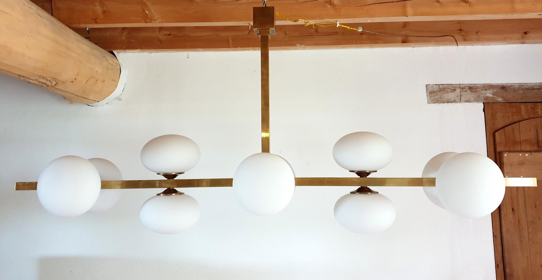 Extra long horizontal Mid-Century Modern chandelier, made with brass mounts and ten white glass globes.
Italy, 1970s.
10-light, rewired for the US.
The perfect shape for over a long table, kitchen island, or billiard.
In excellent condition.
 