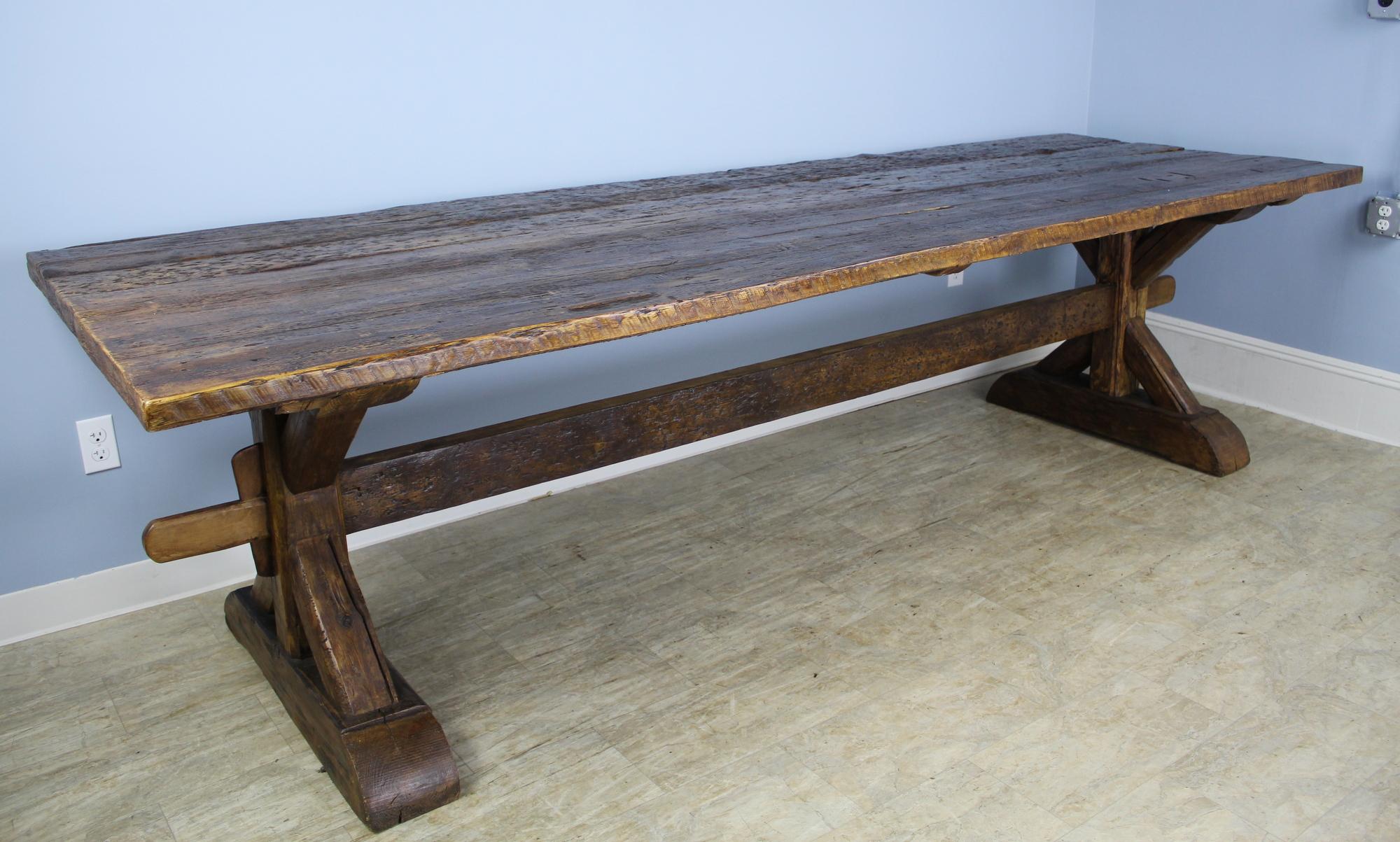 A handsome and beautifully crafted antique French refectory table with a 2 inch thick top and marvelous construction and design on the trestle base. The rustic surface on the tabletop adds an additional note of interest. With no apron or legs to get