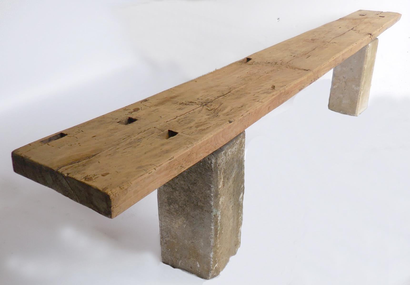 One very long piece of wood top, originally part of a carpenter's bench, atop a pair of old stone bases. All pieces come from the western highlands of Guatemala. Wood has a smooth, naturally worn patina and the natural color of the wood. The bases