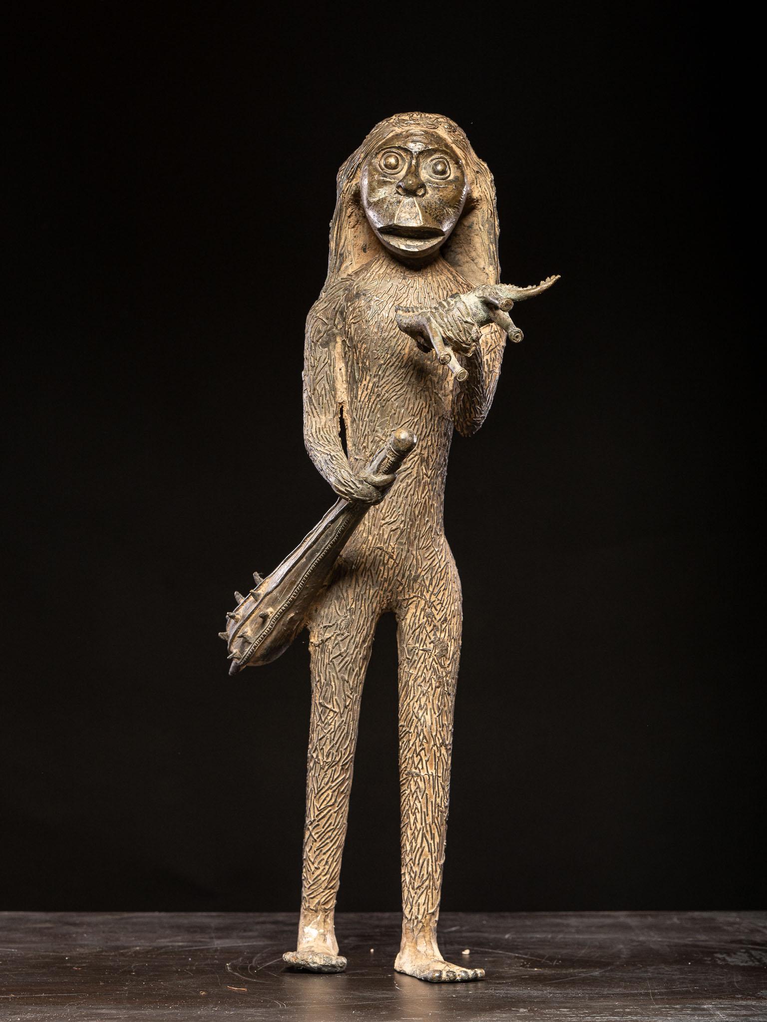 Très mystérieuse et imposante sculpture en bronze représentant un géant mythique, mi-homme, mi-ape, armé d'une massue et s'apprêtant à dévorer un dinosaure tenu dans sa main gauche. Très probablement d'origine africaine, bien qu'il puisse également