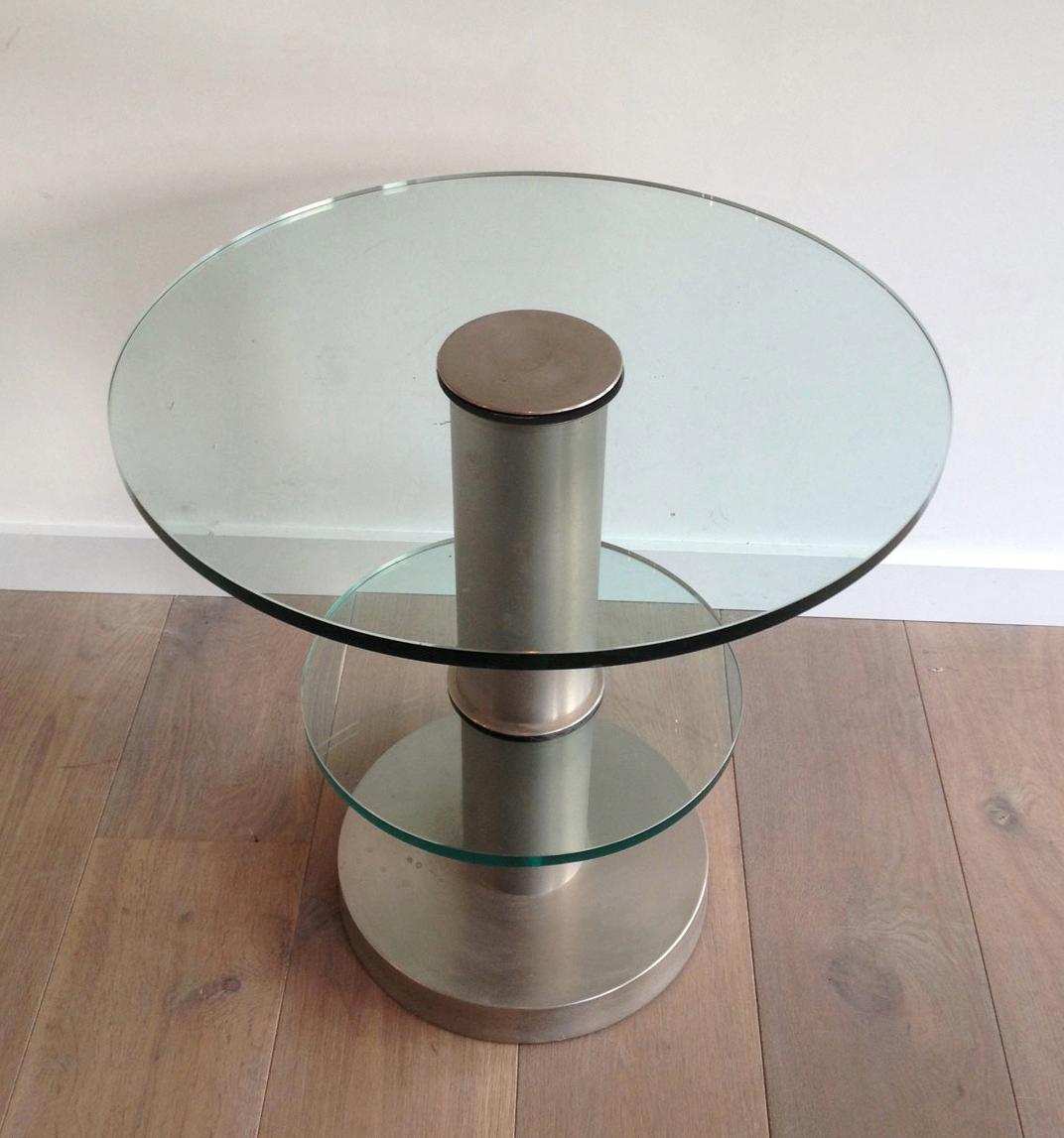 This very nice and interesting modernist round occasionable table is made of brushed metal and two thick pieces of glass. This is a French work, circa 1960.