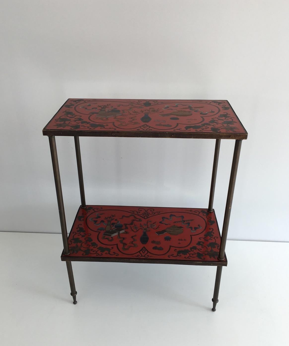 This very nice side table has two shelves which decors are made of cloissonné incrustations on red lacquer, in the style of chinoiserie decors. This is a fine French work, in the style of Maison Bagués. Beautiful piece, probably unique, circa 1960.