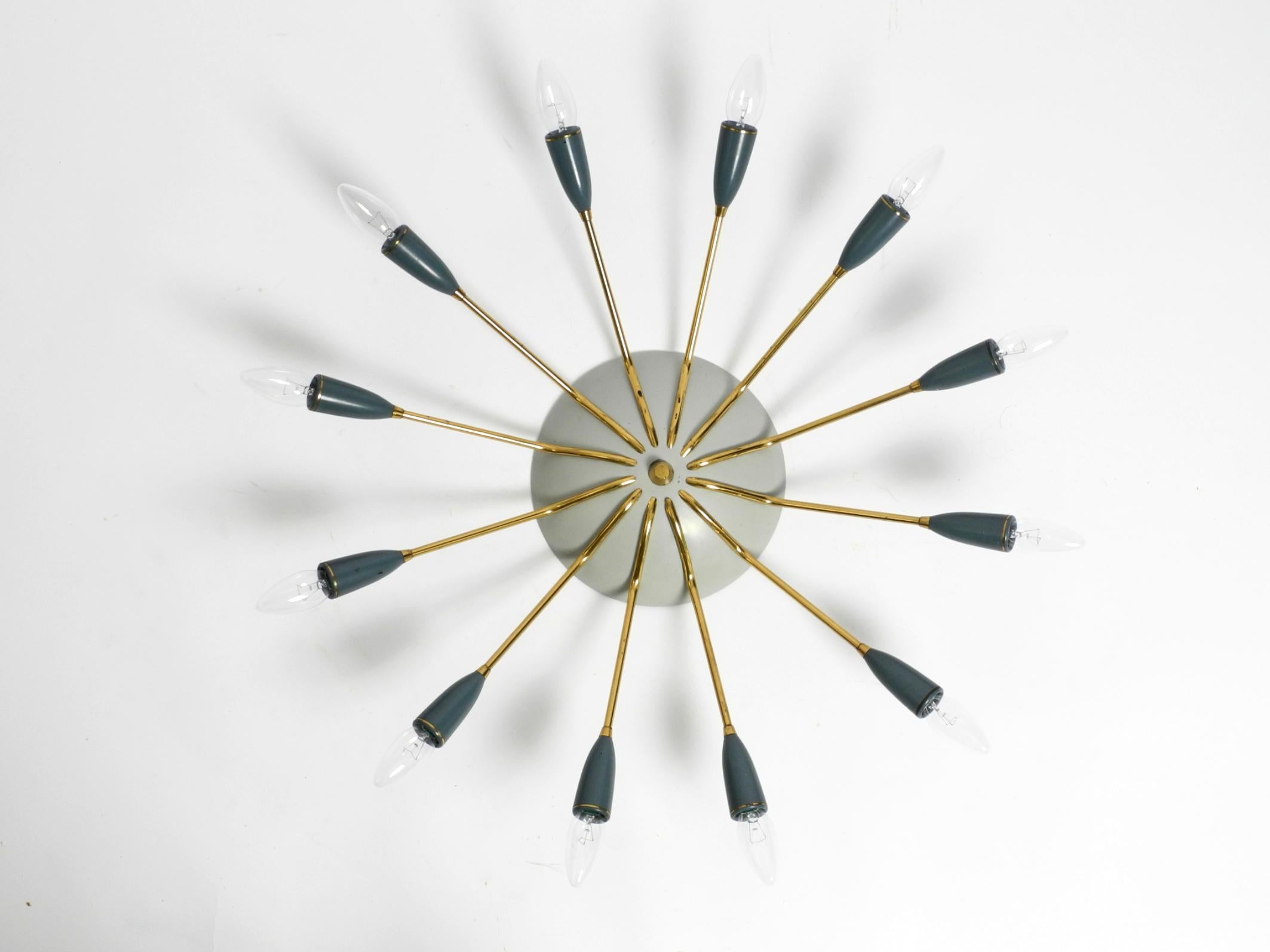 Magnifique grand plafonnier Sputnik moderne du milieu du siècle en laiton avec 12 bras en très bon état, non restauré d'origine. Fabriqué en Allemagne.
Magnifique design minimaliste avec des bras courbés vers le bas en laiton.
Belle patine légère