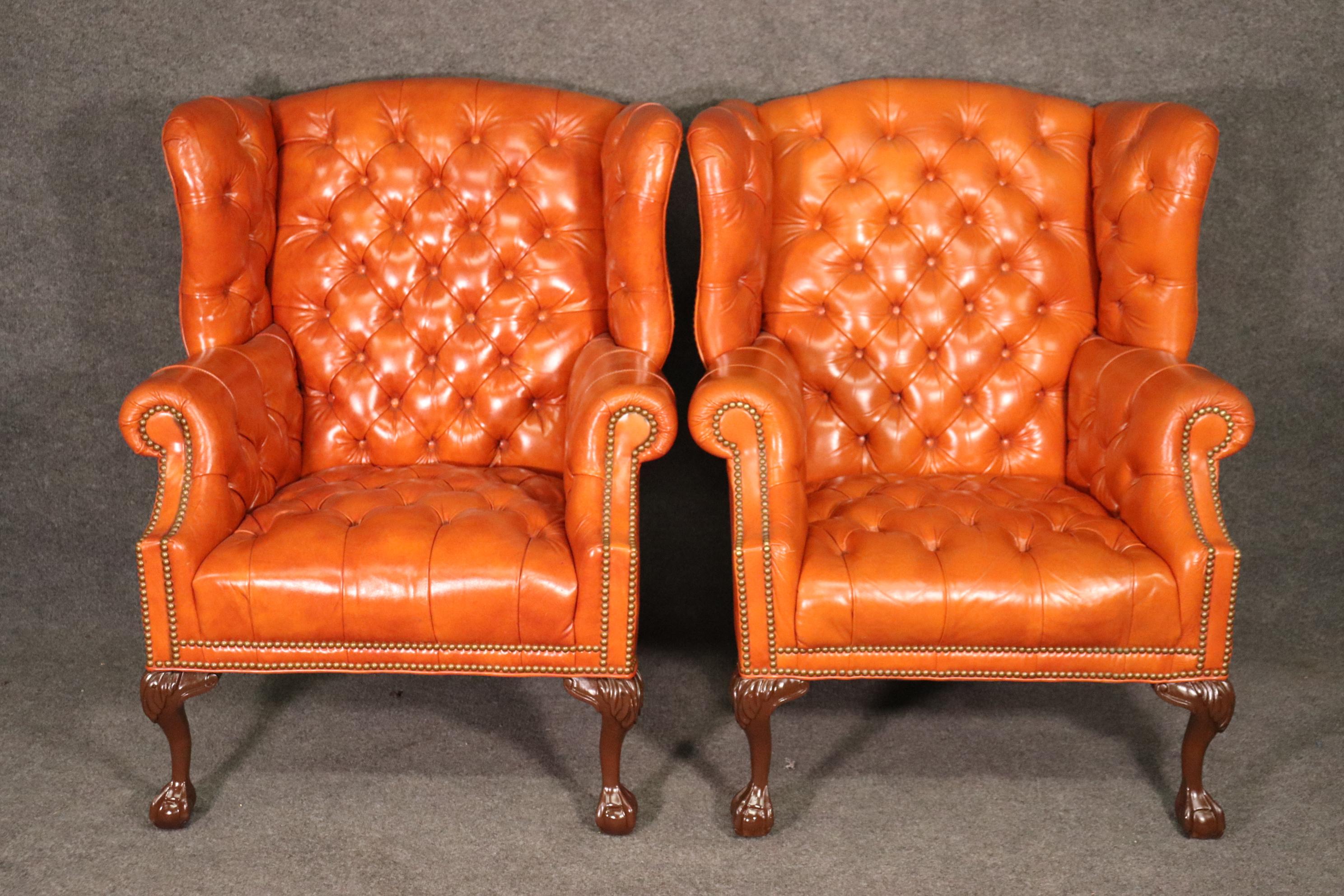 This is a gorgeous set of orange leather wingback chairs with a matching ottoman as well. They are all of generous proportions and in very good antique condition. The chairs measures 42 tall x 34 wide x 36 deep and the stool is 23 wide x 16 tall x
