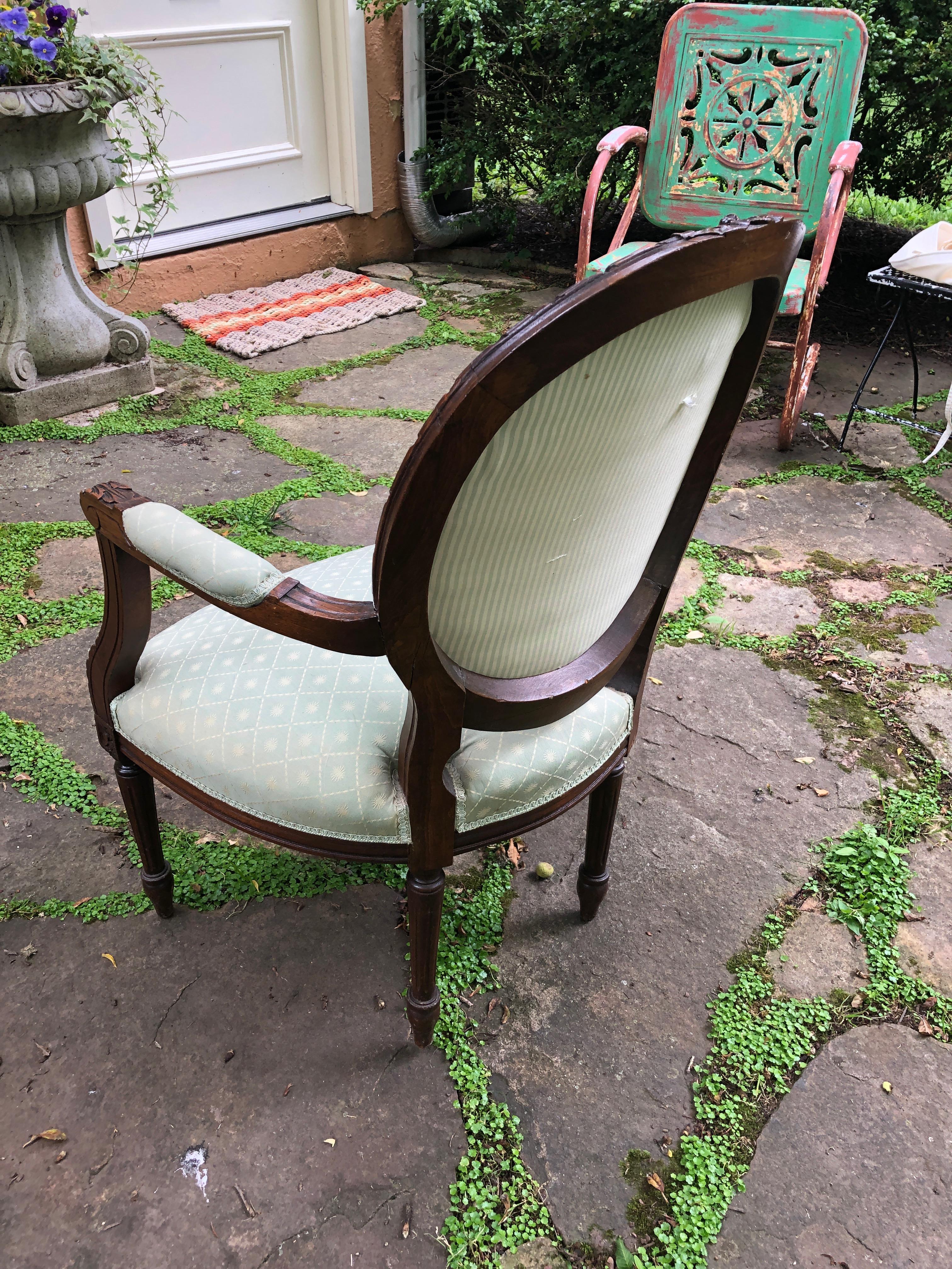 A diminutive but comfortable lovely vintage French armchair bergère having carved walnut frame with acanthus leaves and flower bow at the top, upholstered in original light green silk. Chair also comes with white cotton custom slipcover for back,