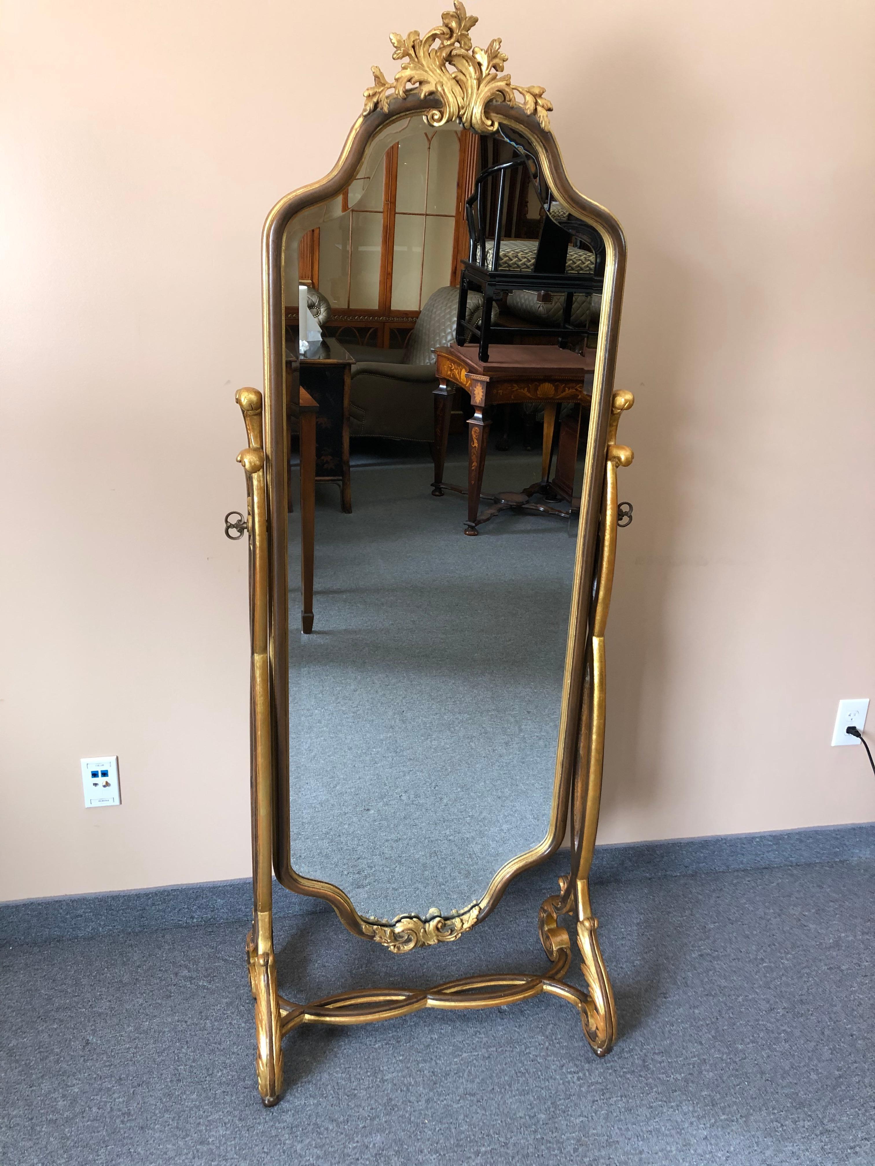 Glamorous standing full length Cheval mirror having gilt decorated wood frame and base, pretty acanthus leaf adornments, beautiful flourish at the top and scalloped shape, as well as a heavy beveled mirror.
Measures: Mirror is 20 W x 55 H.