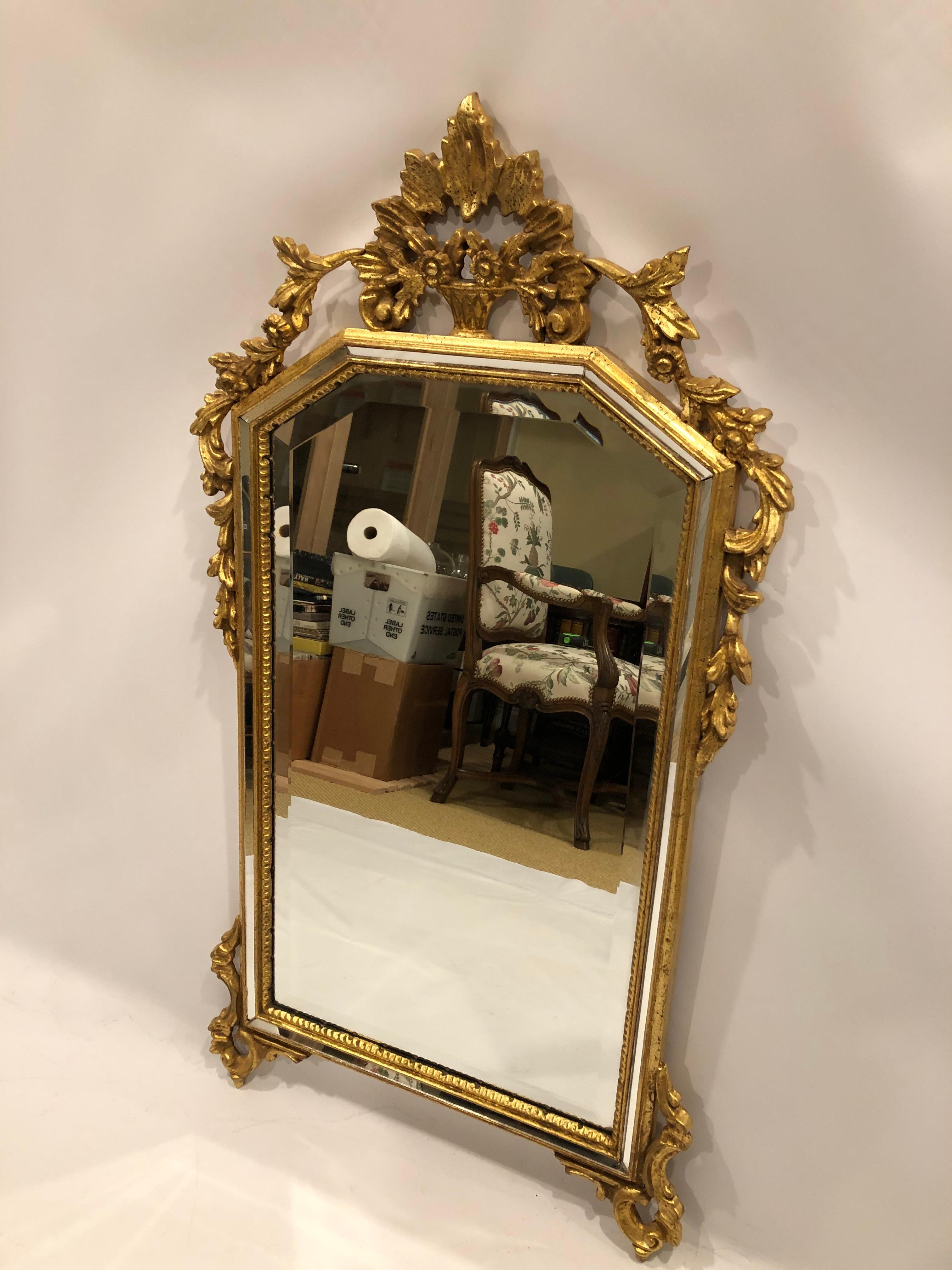 Very pretty carved giltwood mirror having tasteful adornments around the top edges and bottom and lovely triangular crest at the top. A special touch is the inlaid narrow bands of mirror that create a border within the frame.