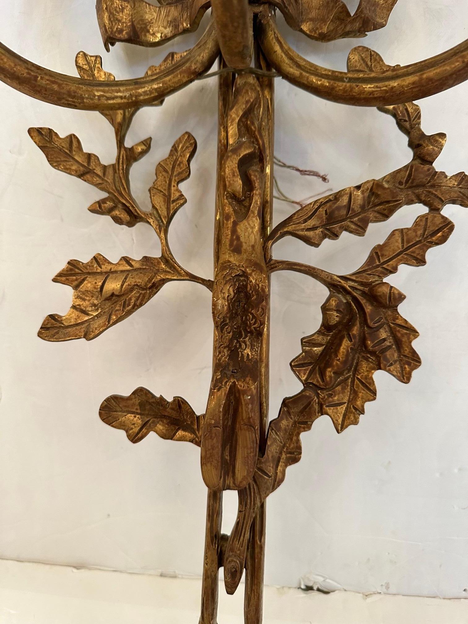 Very pretty large French aged brass wall sconces having 3 lights each and intricate details such as bows and carved foliage.  Brass has been treated to look antique.