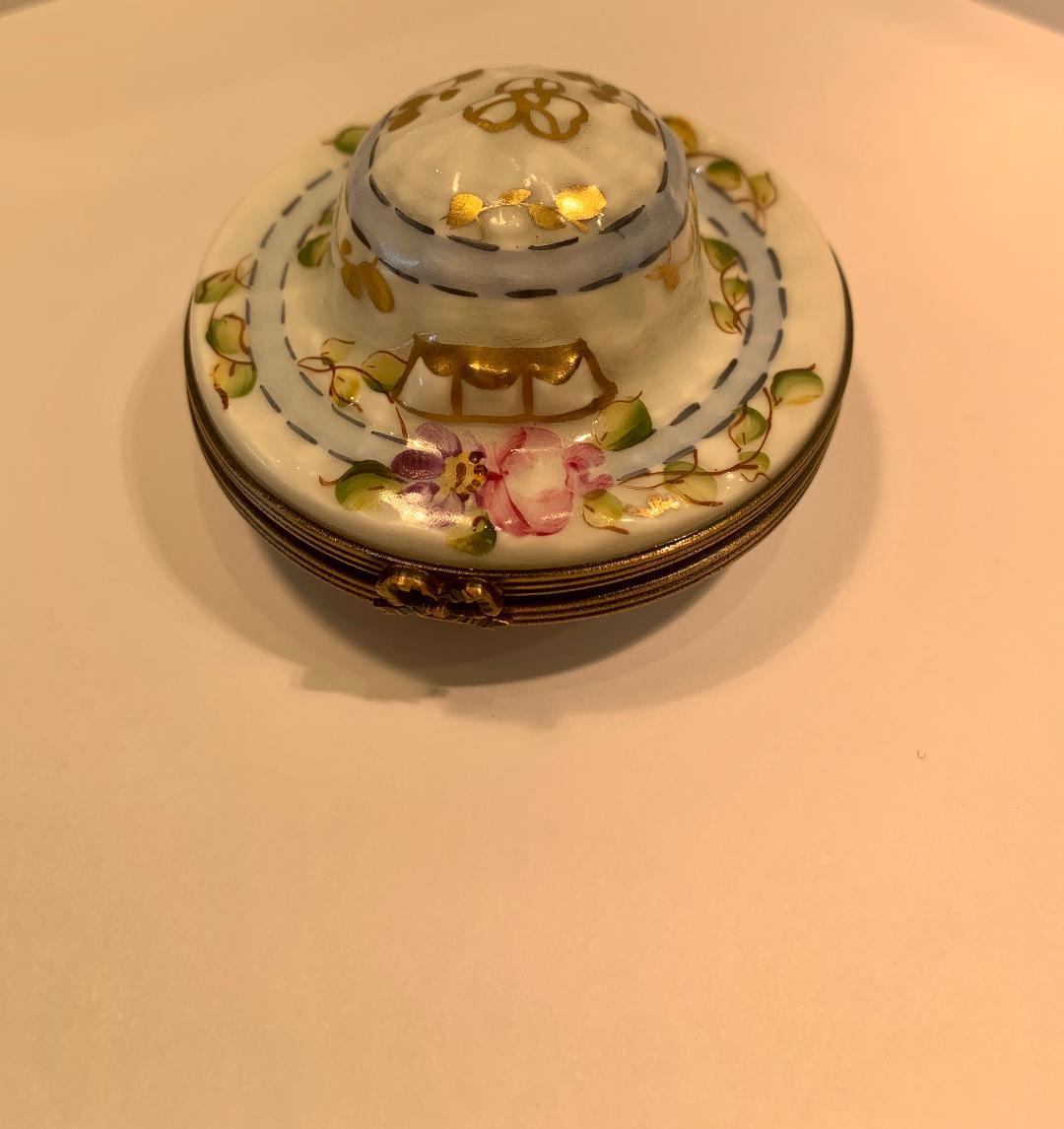 Very pretty, Limoges porcelain miniature hat shaped trinket box is handmade and hand painted in France and features vining floral motif with rich 24-karat gold accents. Box features antiqued gold gilt metal fittings and trim with a sweet 