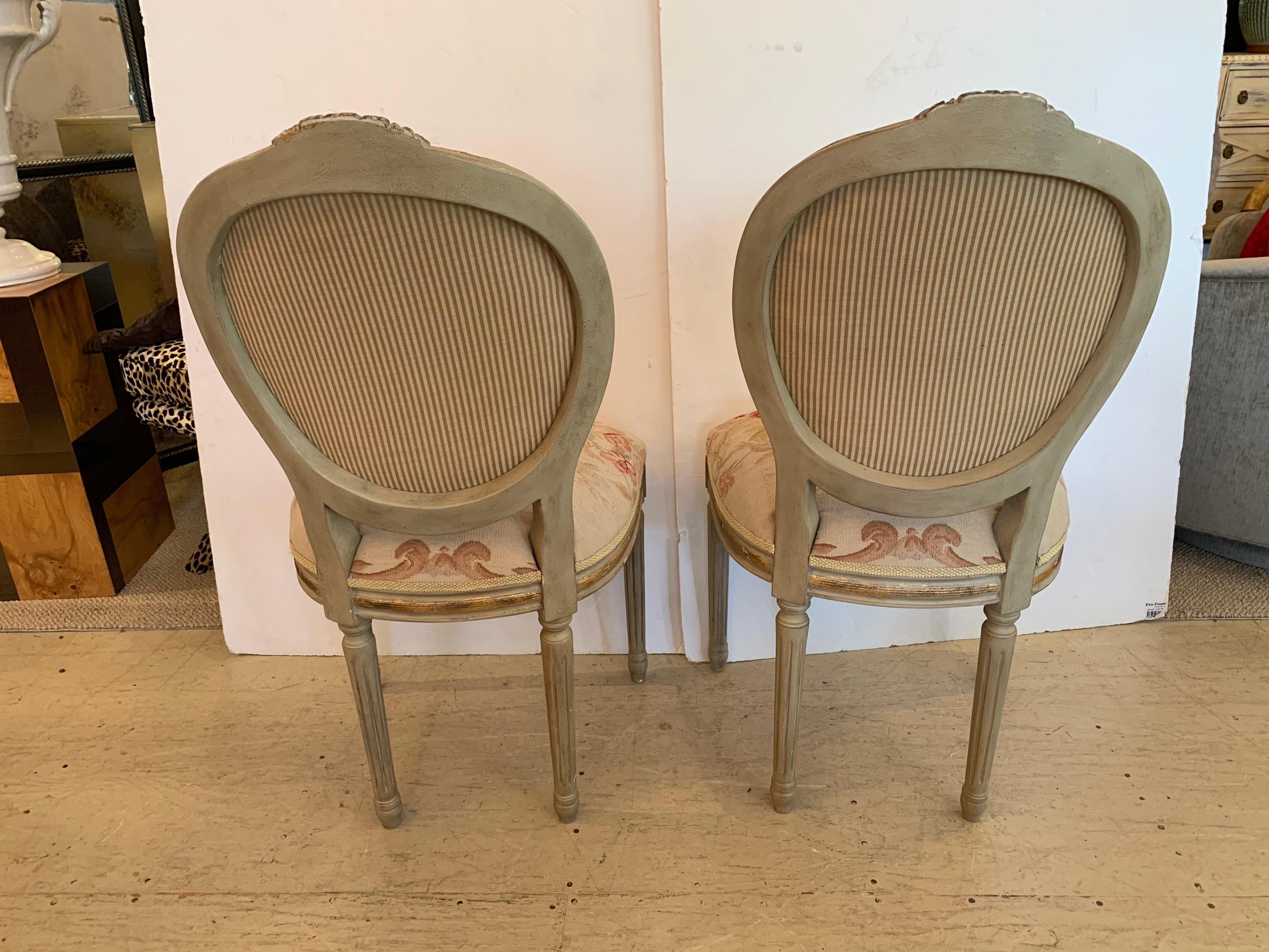 A very pretty pair of Louis XVI style oval back fauteuils or side chairs from French Market, having lovely painted and gilded wood frames in soft light green, upholstered in a soft pastel wool and silk petit point upholstery, and a lovely window