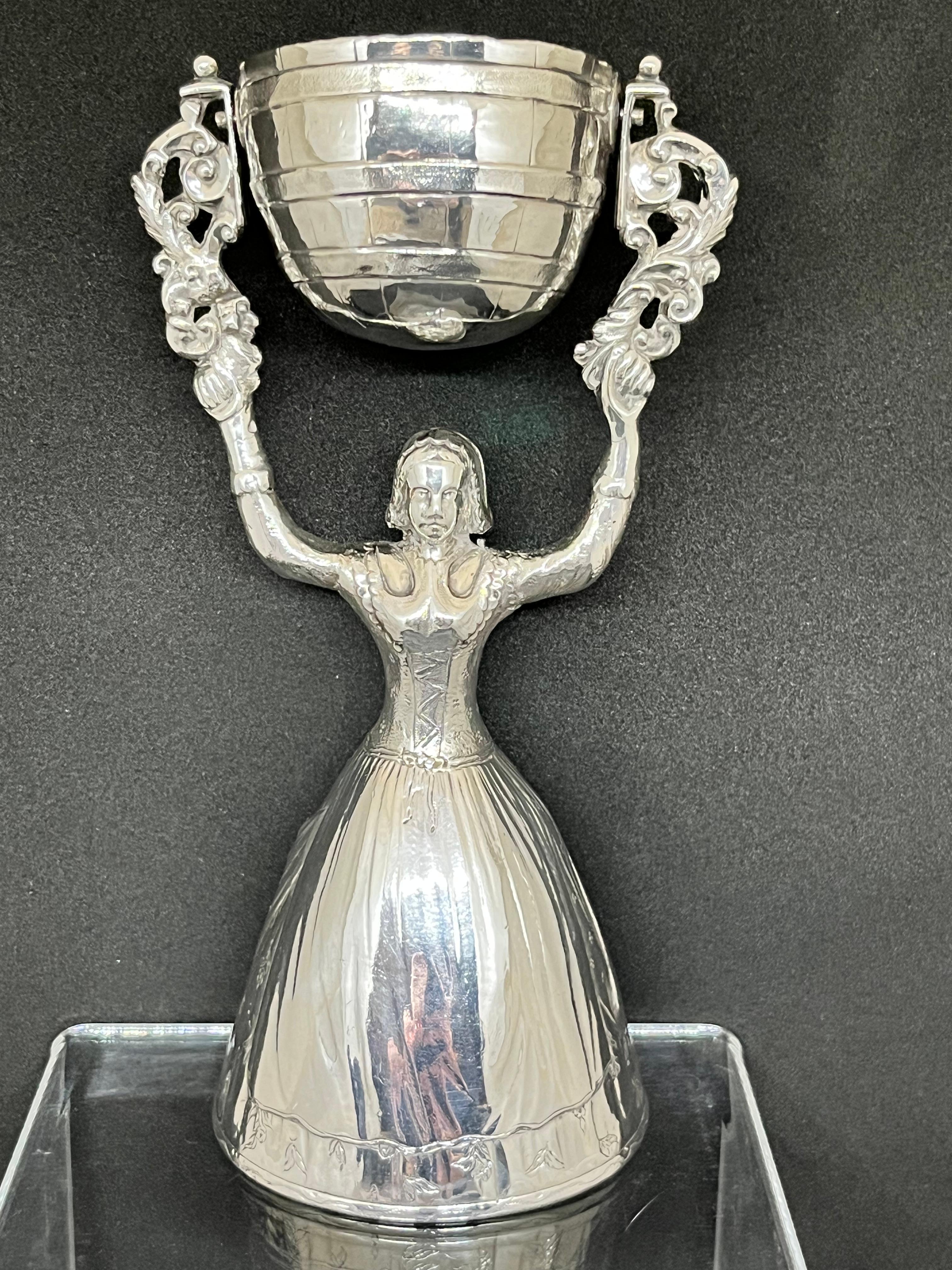 An extremely rare and sought-after 18th-century George III sterling silver hallmarked marriage cup or wager cup, formed as a figure of a woman with flared skirt, holding aloft a pivoted bowl.

This vessel is believed to serve two purposes, both of