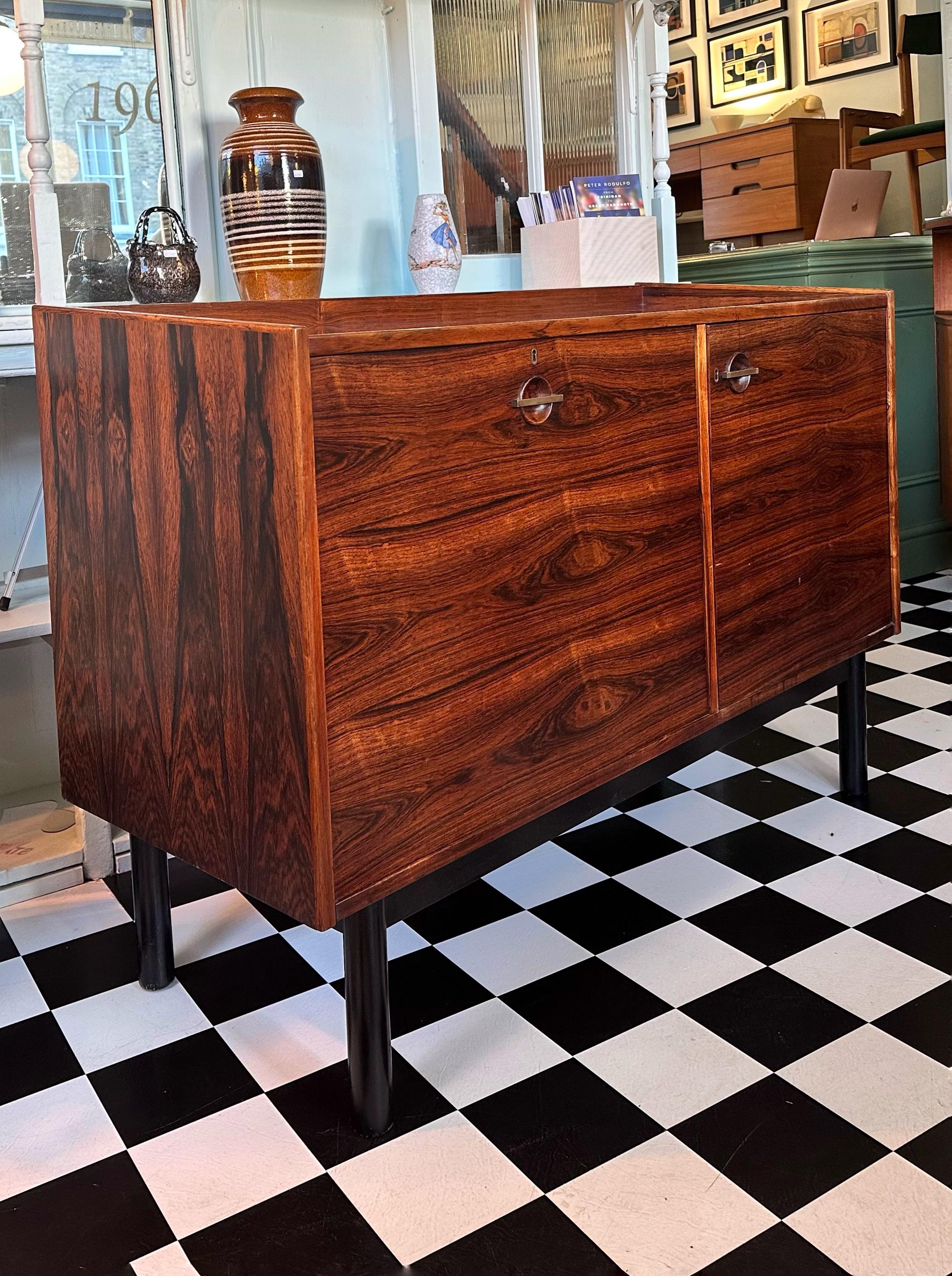 
This 1960’s Mid-Century Danish Rosewood Drinks Cabinet is truly a show-stopping piece that is guaranteed to be the talking point of any room. Crafted from rosewood, this exquisite vintage bar cabinet features stunning wood grain and elegant design