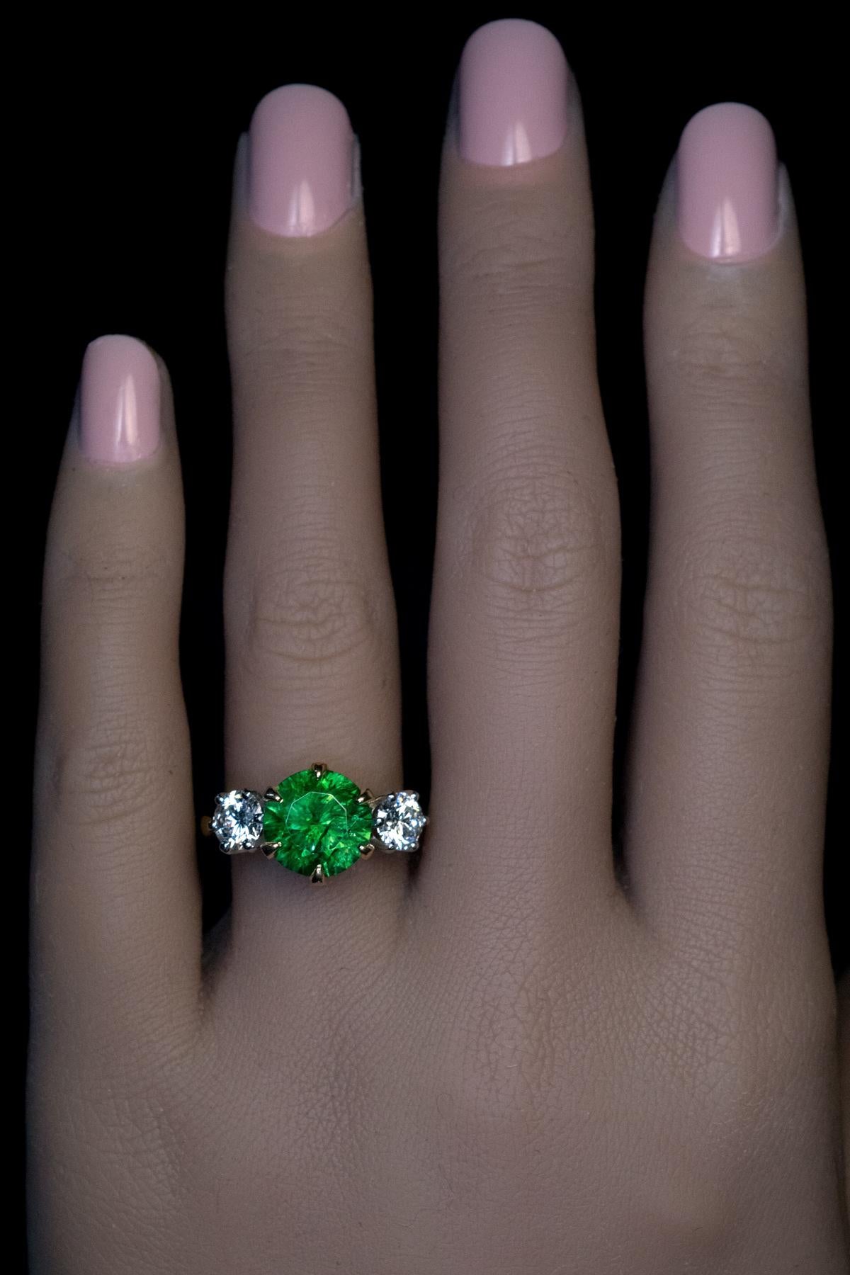 This contemporary three stone ring features a very rare 4.03 ct Russian demantoid of pure green color and excellent brilliance. The demantoid is flanked by two bright white diamonds (0.56 ct and 0.54 ct, G color, VS1 clarity). The ring is crafted in