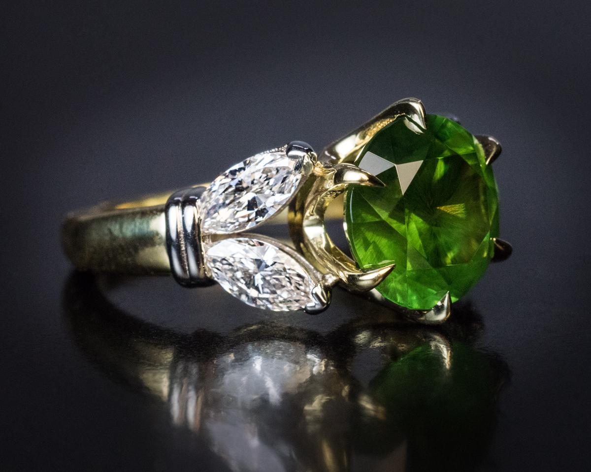 This contemporary ring features a very rare 4.98 ct Russian demantoid from the Ural Mountains. The demantoid is flanked by two pairs of bright white (E-F color, VS clarity) marquise cut diamonds.

The demantoid measures 10.08 x 10.05 x 6.72 mm and