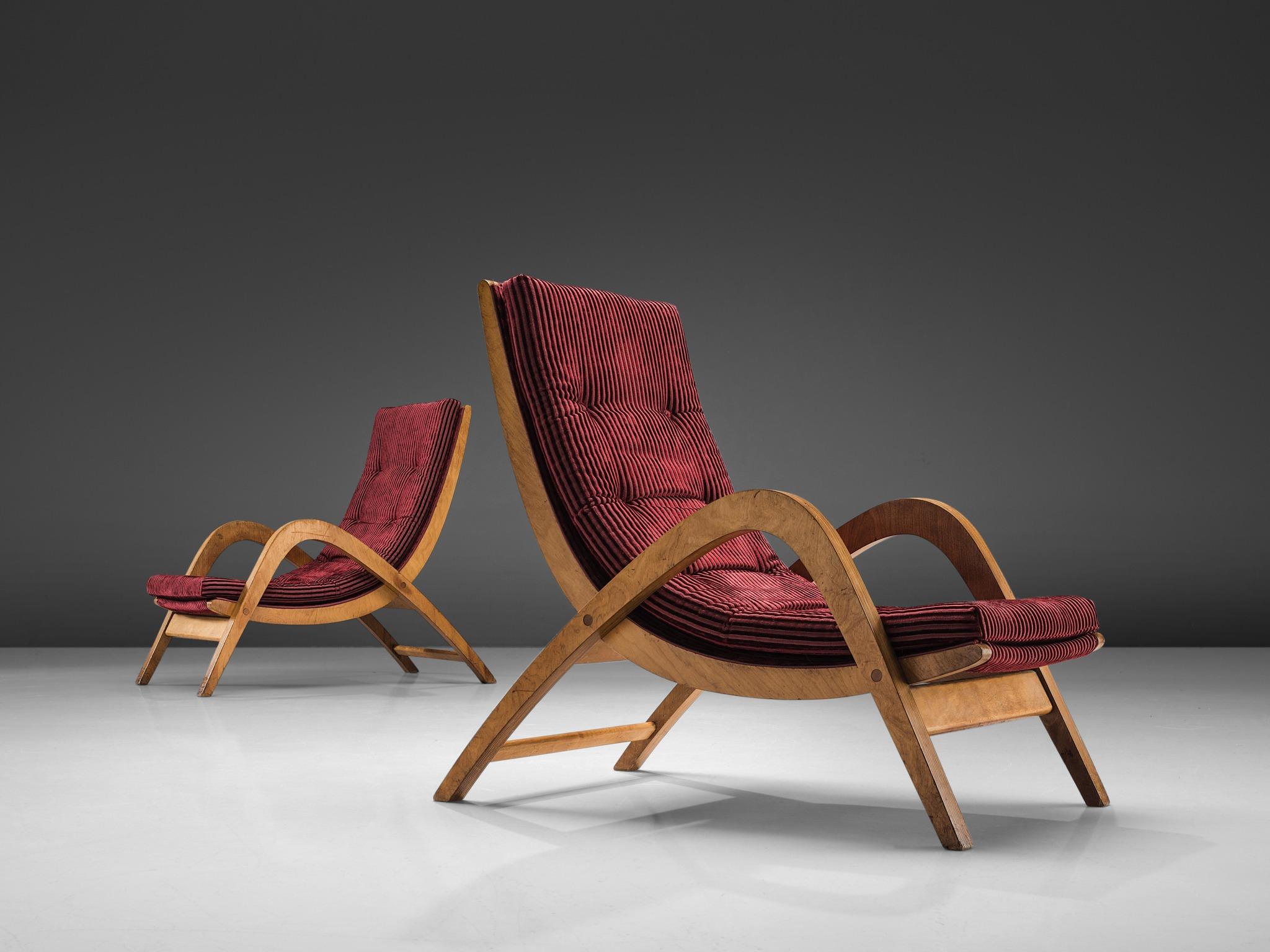 Neil Morris for H. Morris, lounge chairs, burgundy red upholstery and plywood, Scotland, 1940s. 

These wavy, elegant armchairs have both a high back and high armrests and together create the high character of these very large lounge chairs. The