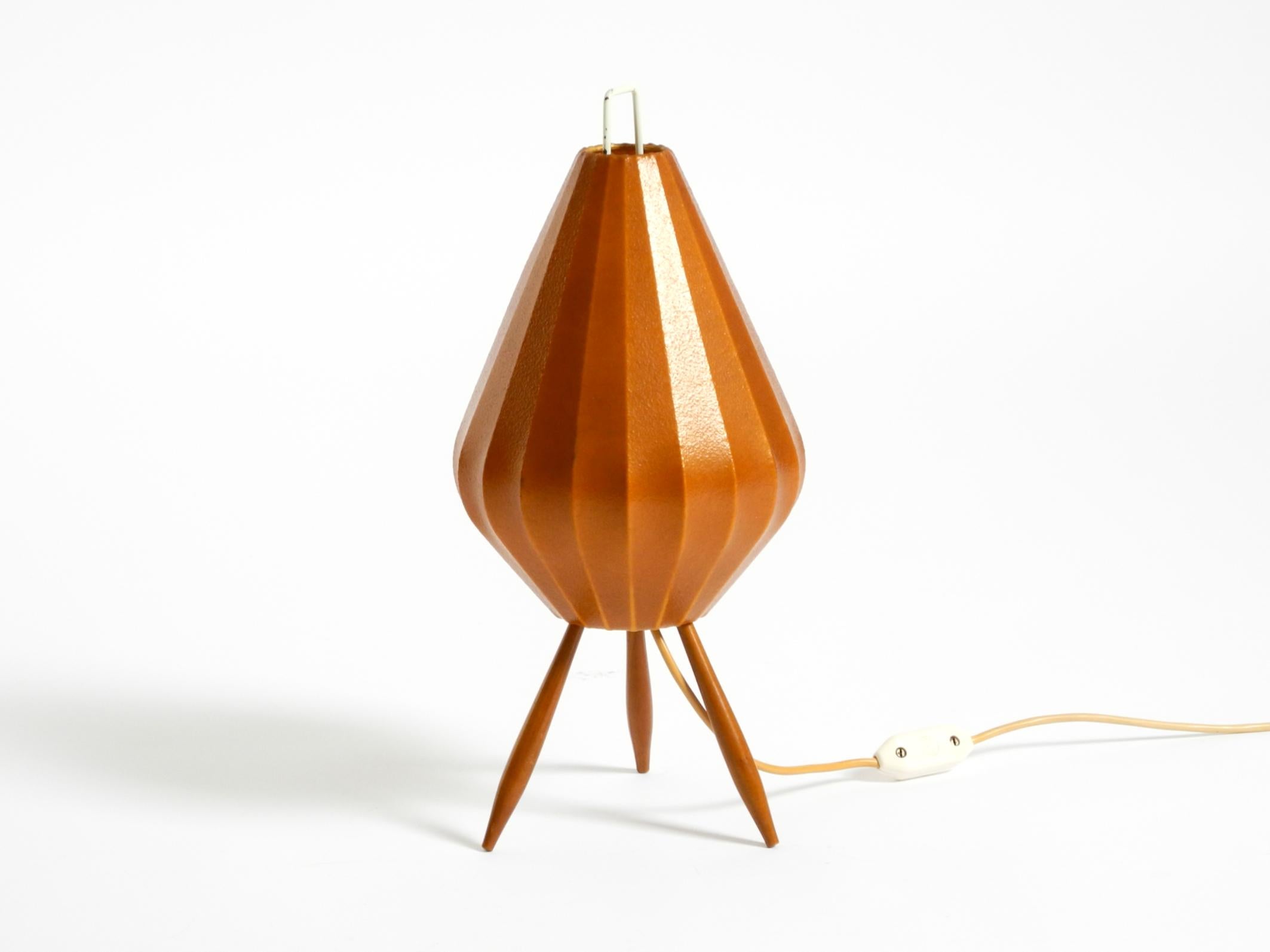 Very rare Mid-Century Modern tripod table lamp with an original brown-red cocoon shade.
Great minimalist 1950s design.
Produces a very pleasant, warm light.
Very good original vintage condition.
The cocoon shade is in very good condition.
The wooden
