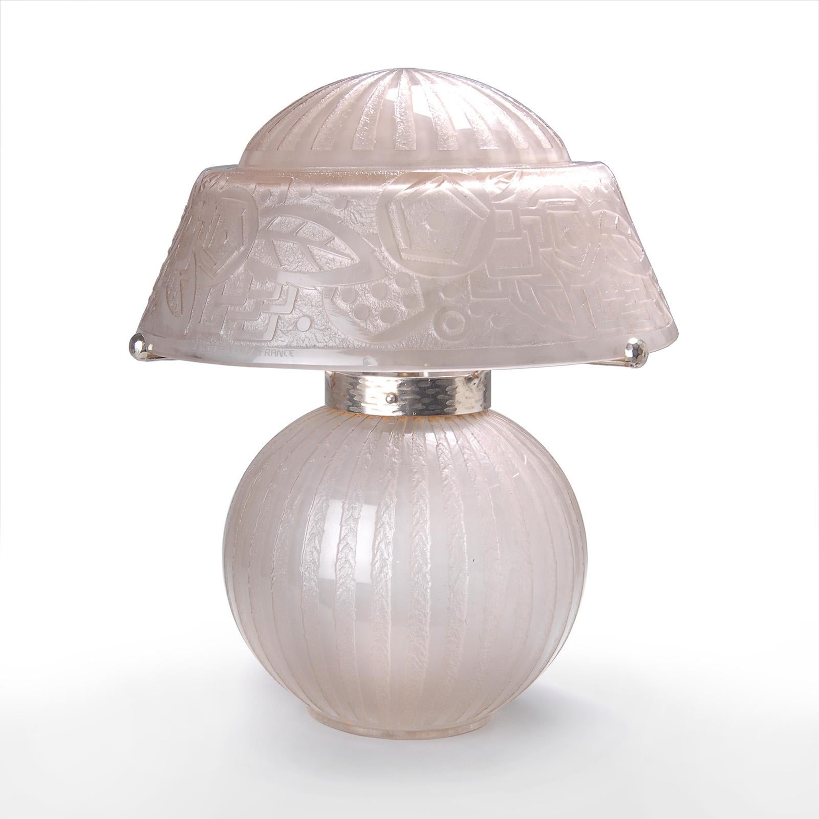 Lámpara de sobremesa Art Déco Daum Freres Nancy.
Cristal incoloro ahumado rosáceo, grabado al agua fuerte, con un dibujo geométrico.
Tres brazos de hierro forjado martillado cromado que sujetan la pantalla.
Electrificado, dos tomas de bayoneta, pie