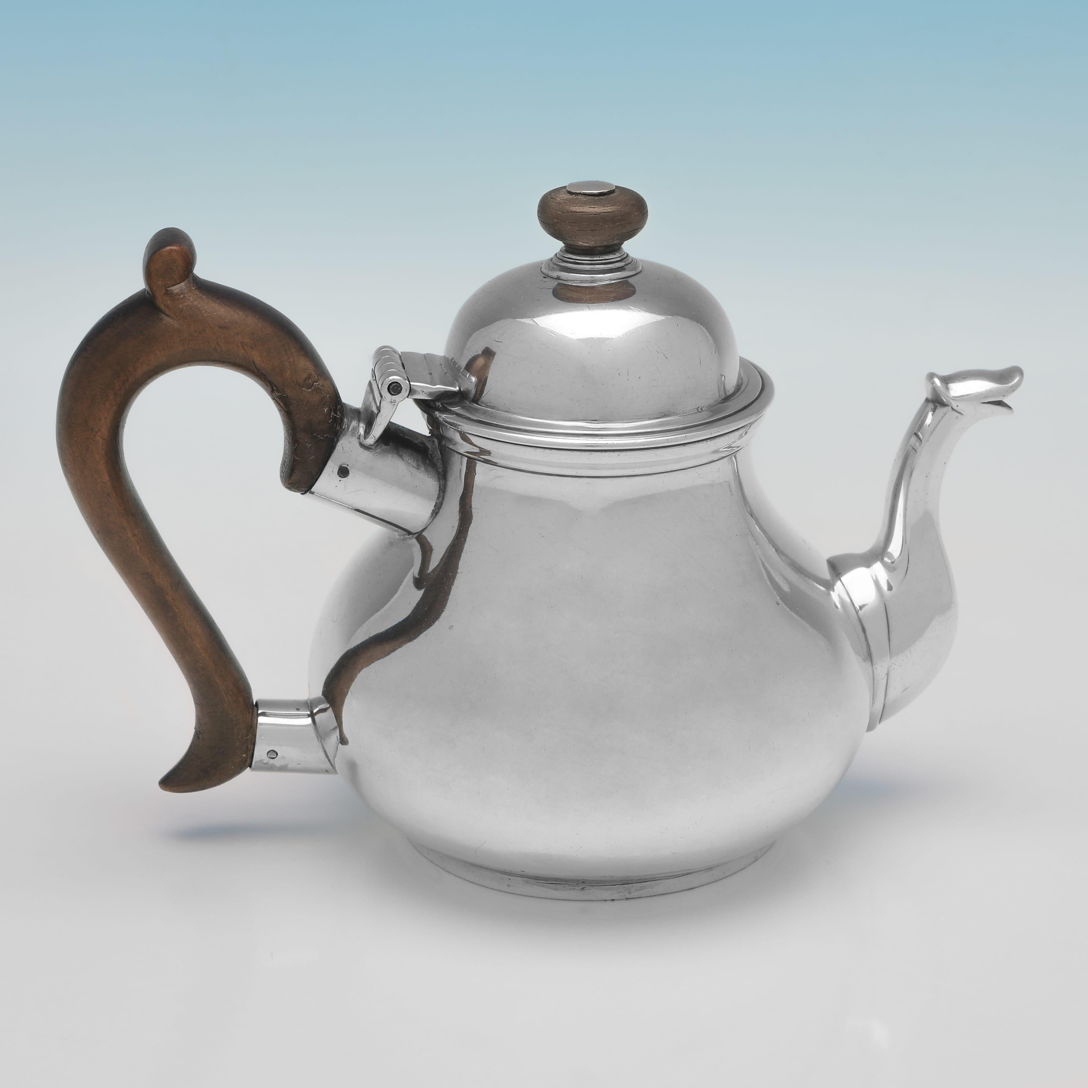 Hallmarked in London in 1725 by William Spackman, this handsome, George I period, Antique Sterling Silver Teapot, is pear shaped, and features a wooden handle and finial, and an engraved coat of arms to one side. 

The teapot measures 5.25