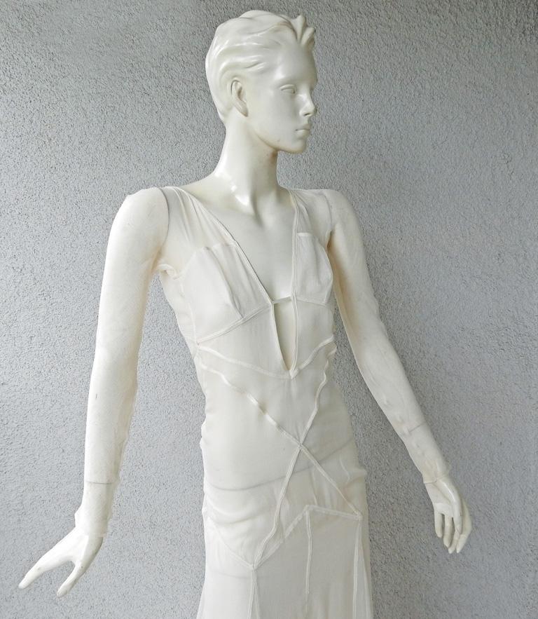 A rare Gucci by Tom Ford 2002 evening dress fashioned in eggshell white outlined in eye catching seam illusion.   Dress boasts a tasteful plunging neckline extending into a full skirt with dramatic train.   Criss-cross design open back.  Side snap