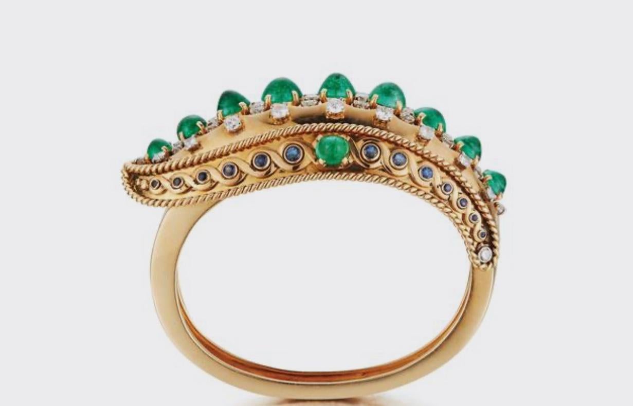Very Rare Indian Influenced Cabochon Emerald Bangle Bracelet by Cartier Paris
11 gem quality cabochon Emeralds
38 round cut diamonds 
26 brilliant cut sapphires 
Internal Curcumfrence is 6.50 inches
Signed Cartier Paris and numbered with maker's